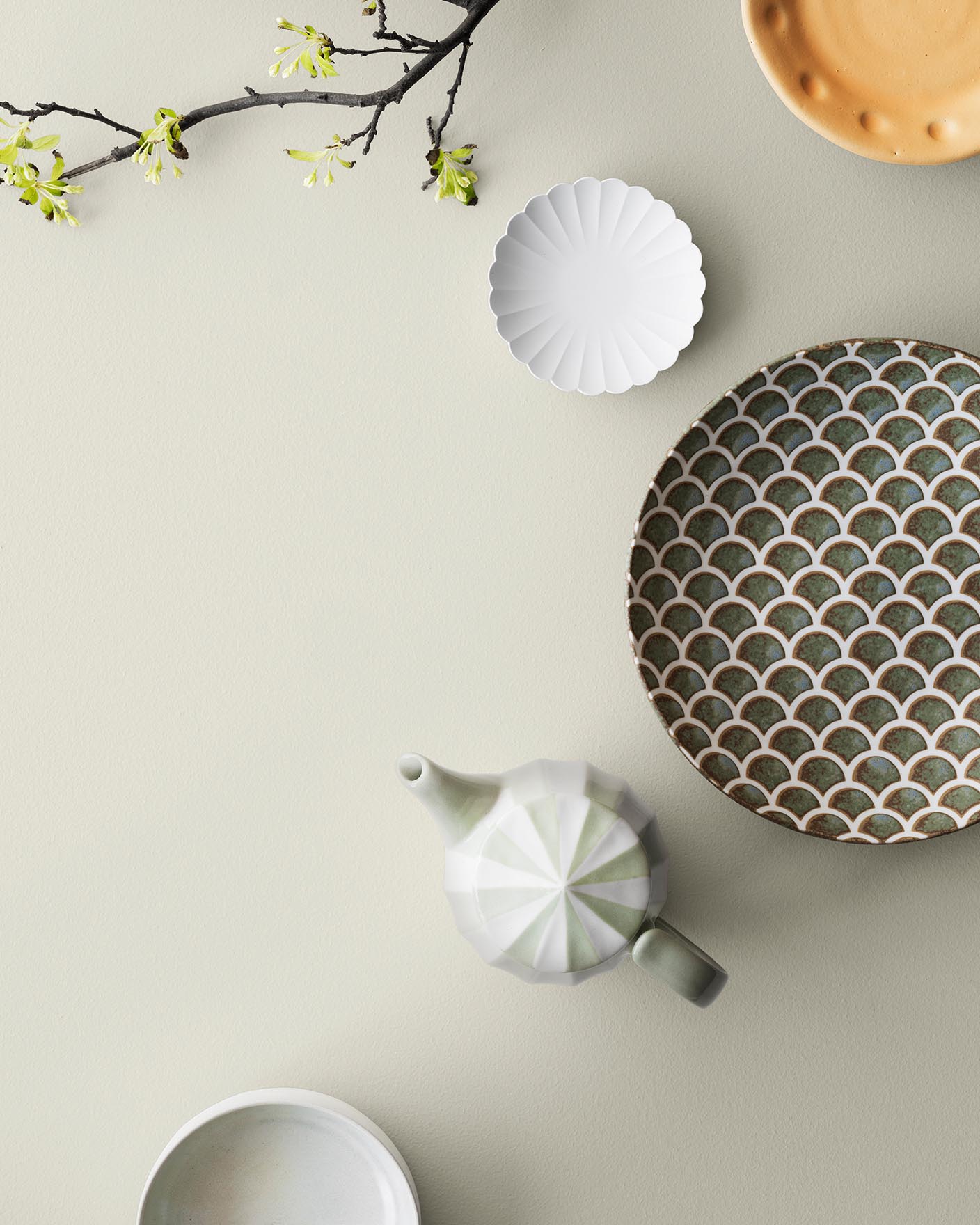 Dekorativt servise og vårgren på en varm, dempet bakgrunn malt med 10678 Space fra Jotun.