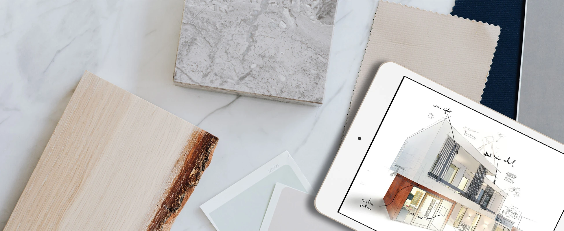 Tablet displaying architectural design surrounded by wood and marble material samples on a light surface