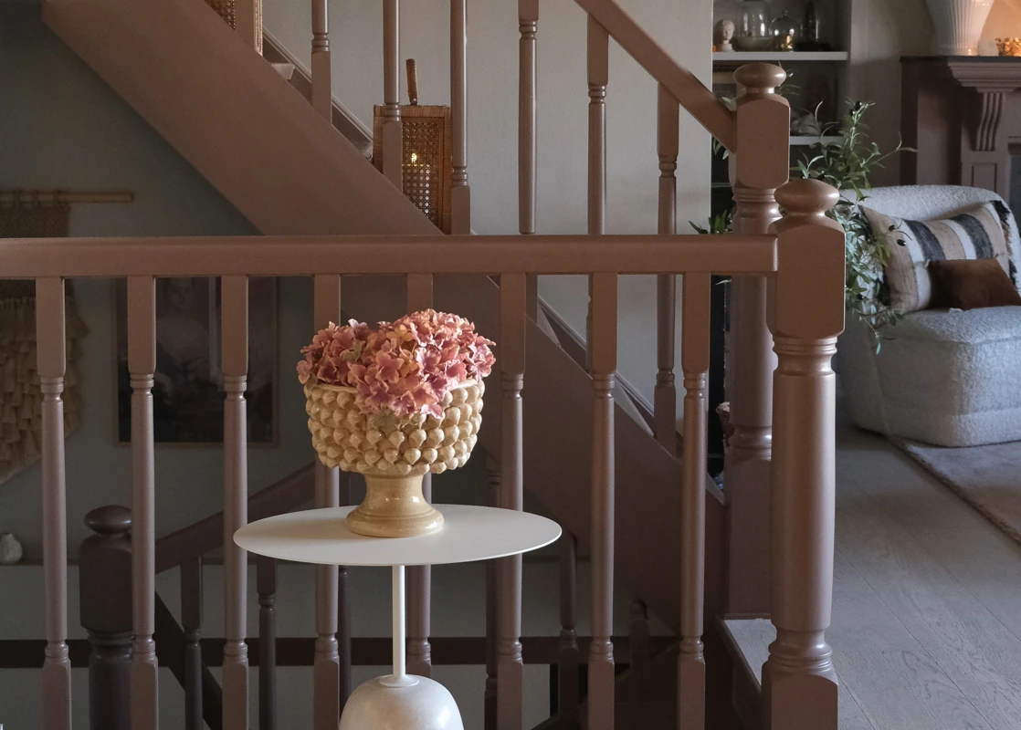 Trapp malt i rødbrunt med Jotun LADY Mellow, lyse vegger i fargen Jotun Space, stue i bakgrunnen med peis malt i Jotun Mellow.