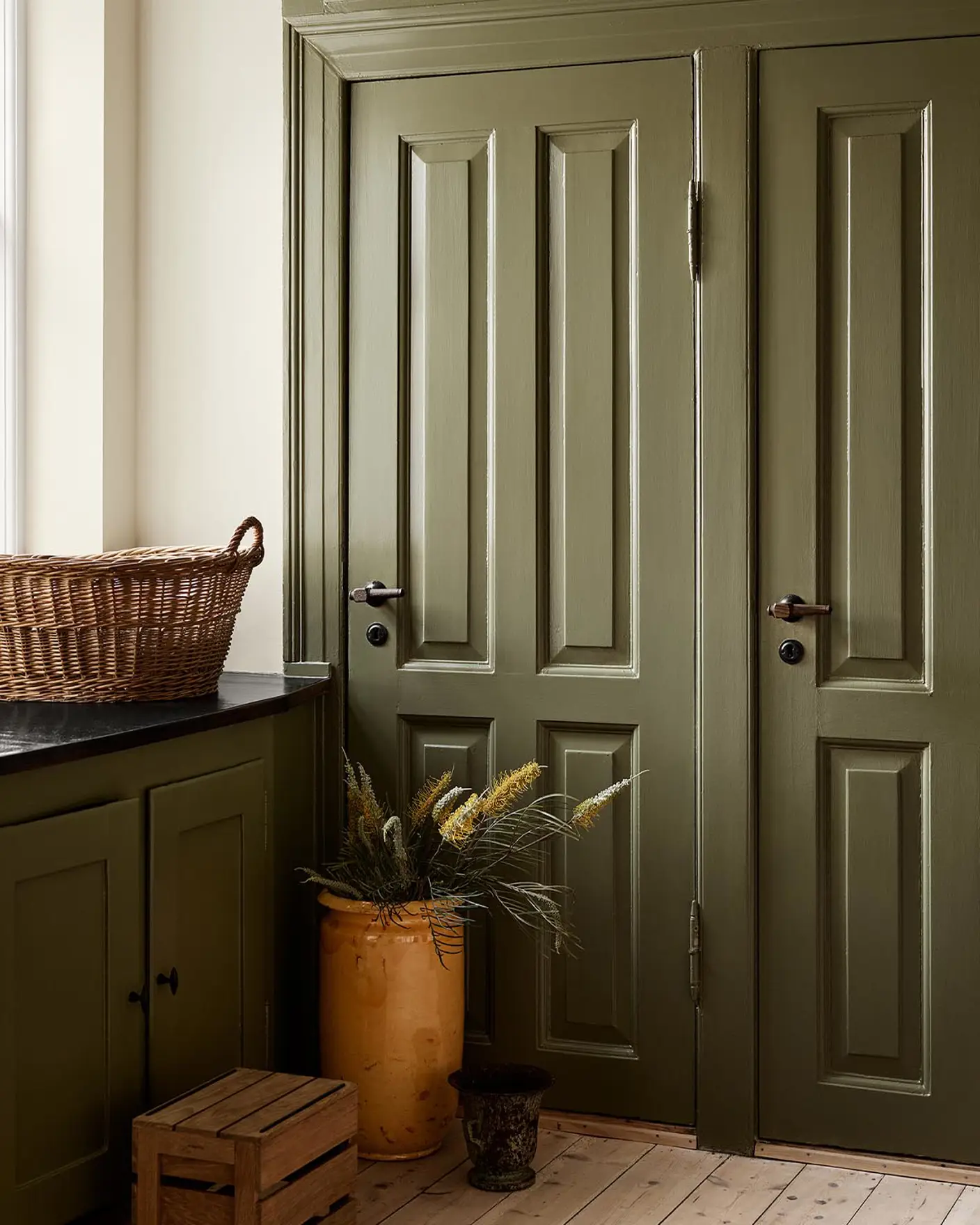 Kitchen with olive-green cabinets in the colour 8597 Seaweed Green against a muted yellow wall painted with 12079 Gleam from Jotun.
