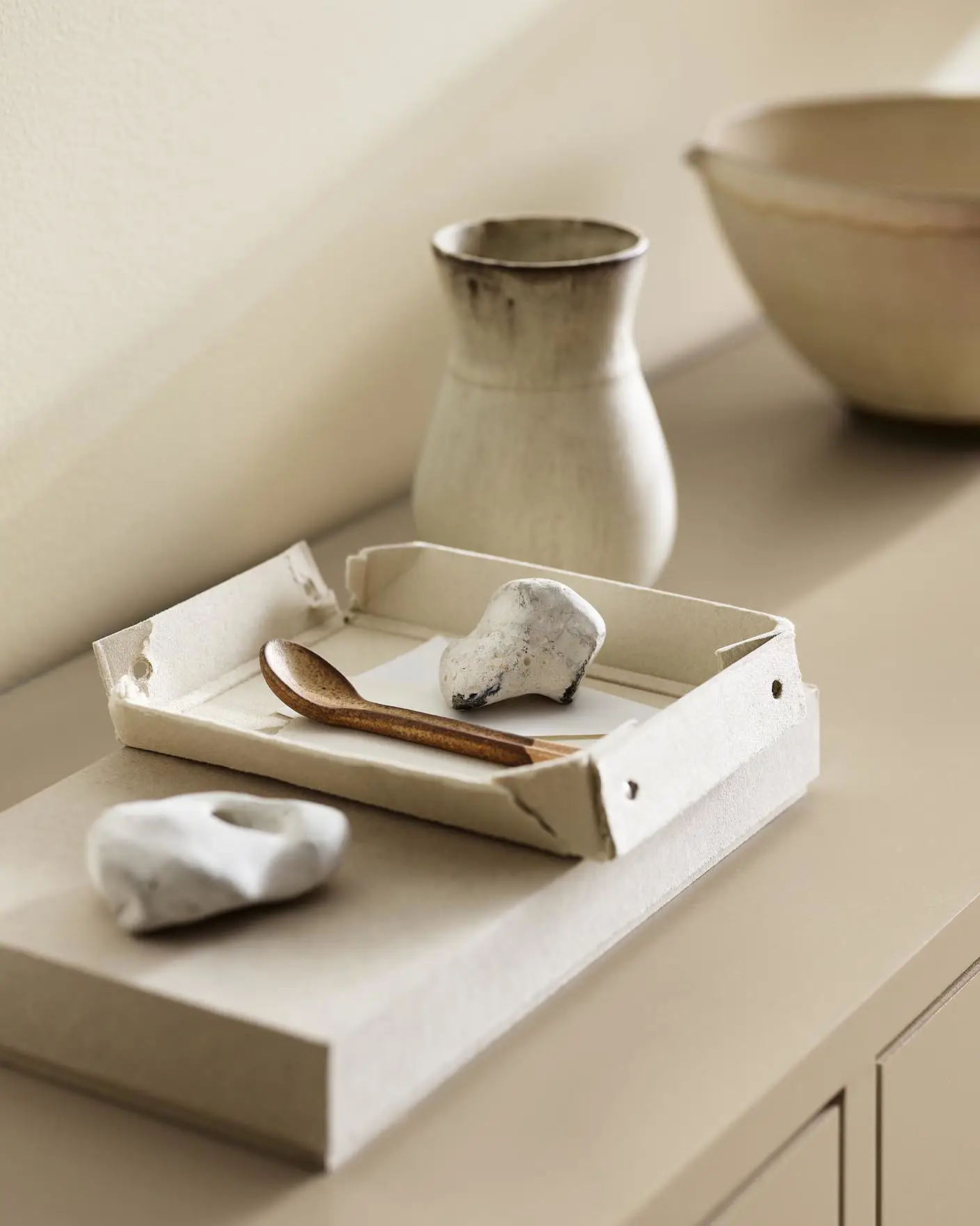A ceramic vase, tray, and white stones against a wall painted with the colour 1625 Soul from Jotun.