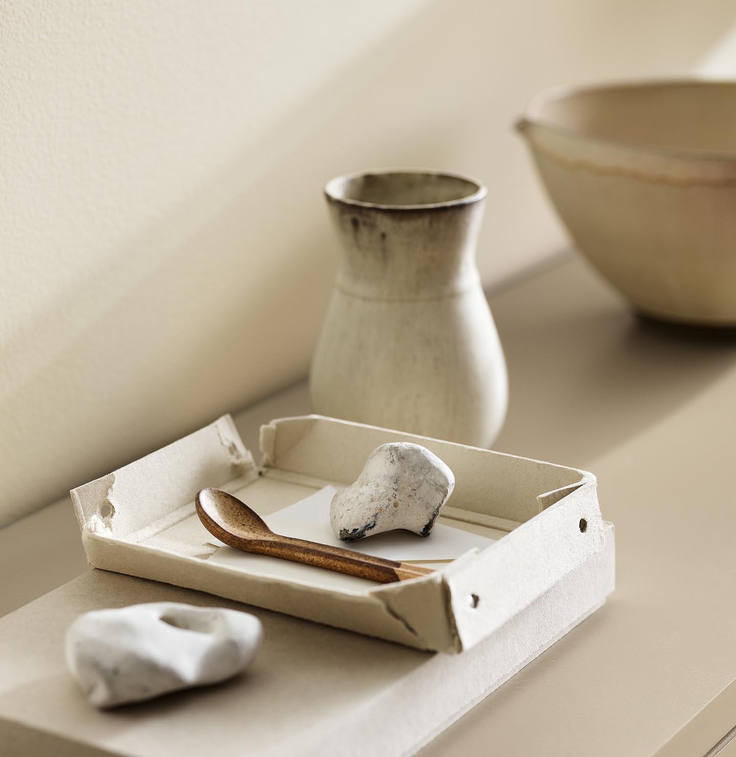A ceramic vase, tray, and white stones against a wall painted with the colour 1625 Soul from Jotun.
