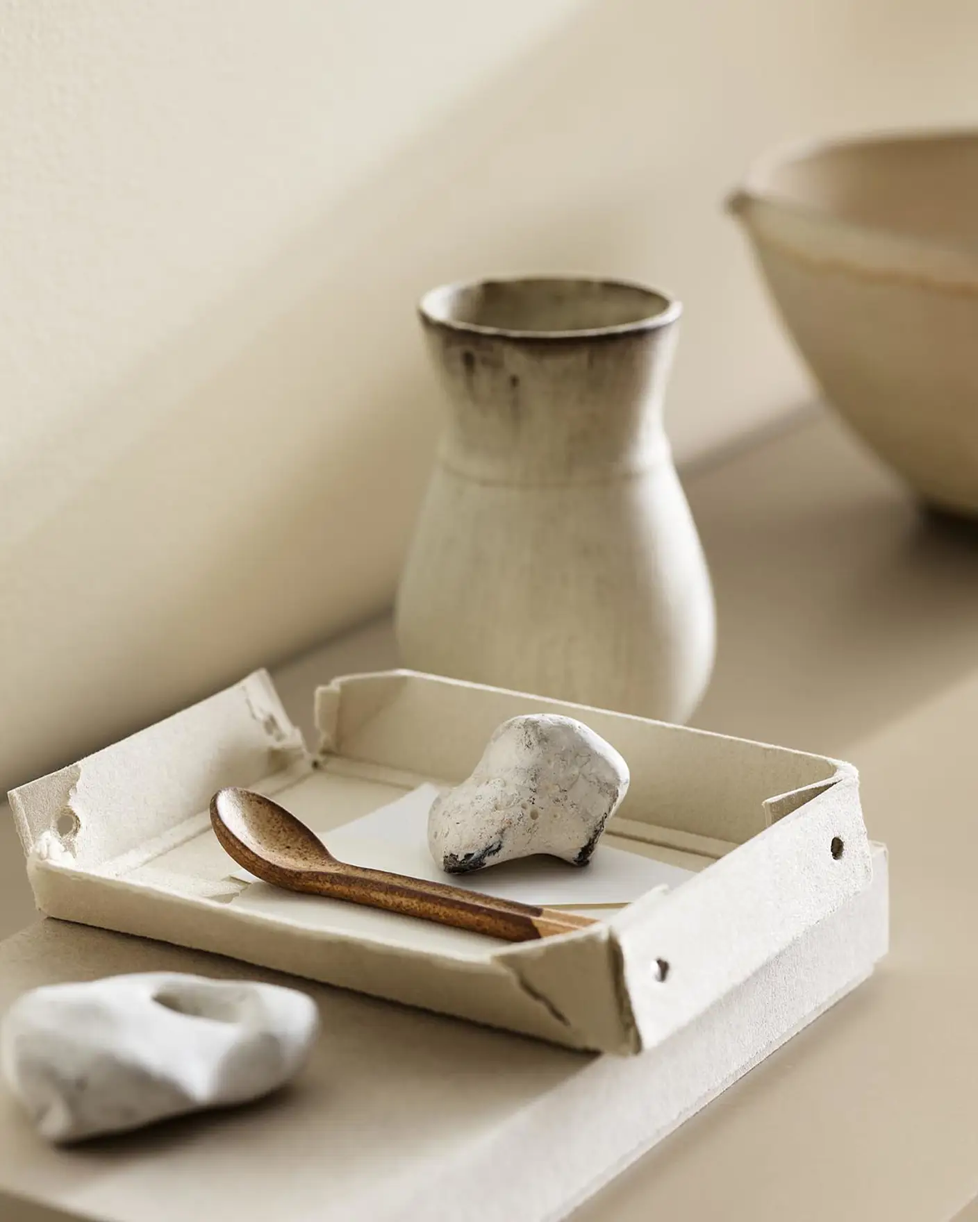 A ceramic vase, tray, and white stones against a wall painted with the colour 1625 Soul from Jotun.