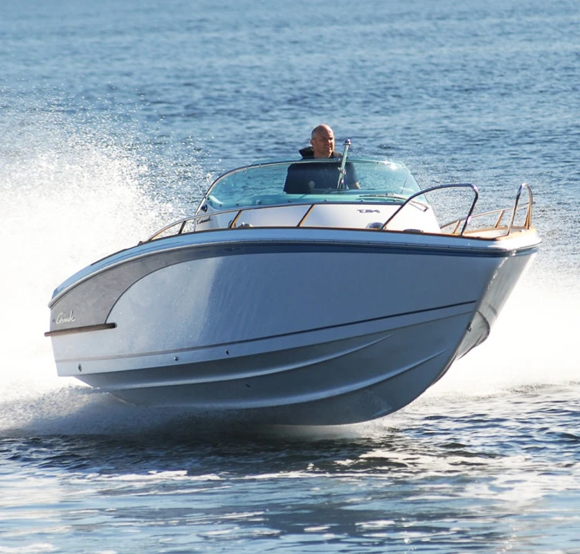 Hurtiggående motorbåt i plan på rolig sjø med sollys over vannet.