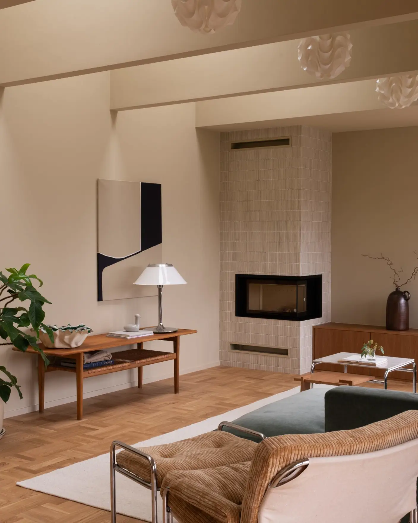 Lyst og moderne stue med parkettgulv, en sofa foran en stor vindu, to designstoler, og en peis. En plante står ved et sidebord med lampe og kunstverk. Minimalistisk skandinavisk interiør, vegger og tak malt i Jotun 11173 Humble Yellow