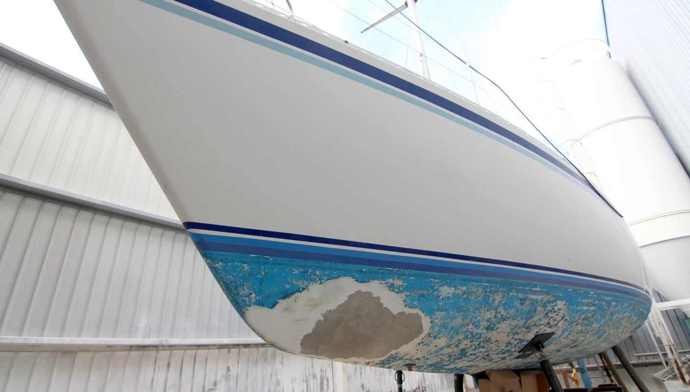 Båt med slitent skrog på bukker klart for pussing og vedlikehold med Jotuns båt-produkter.