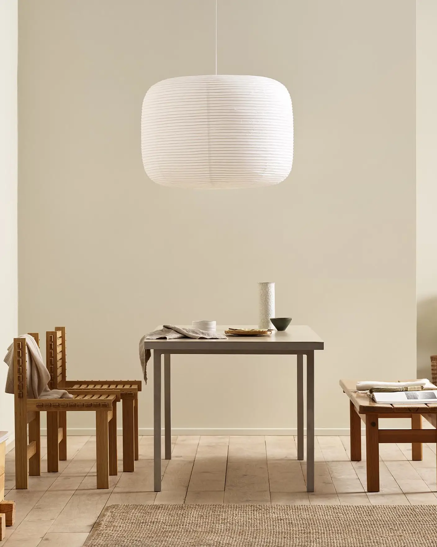 Minimalist dining area with wooden chairs, pendant light, and golden beige walls painted with the colour 12308 Unbleached from Jotun.