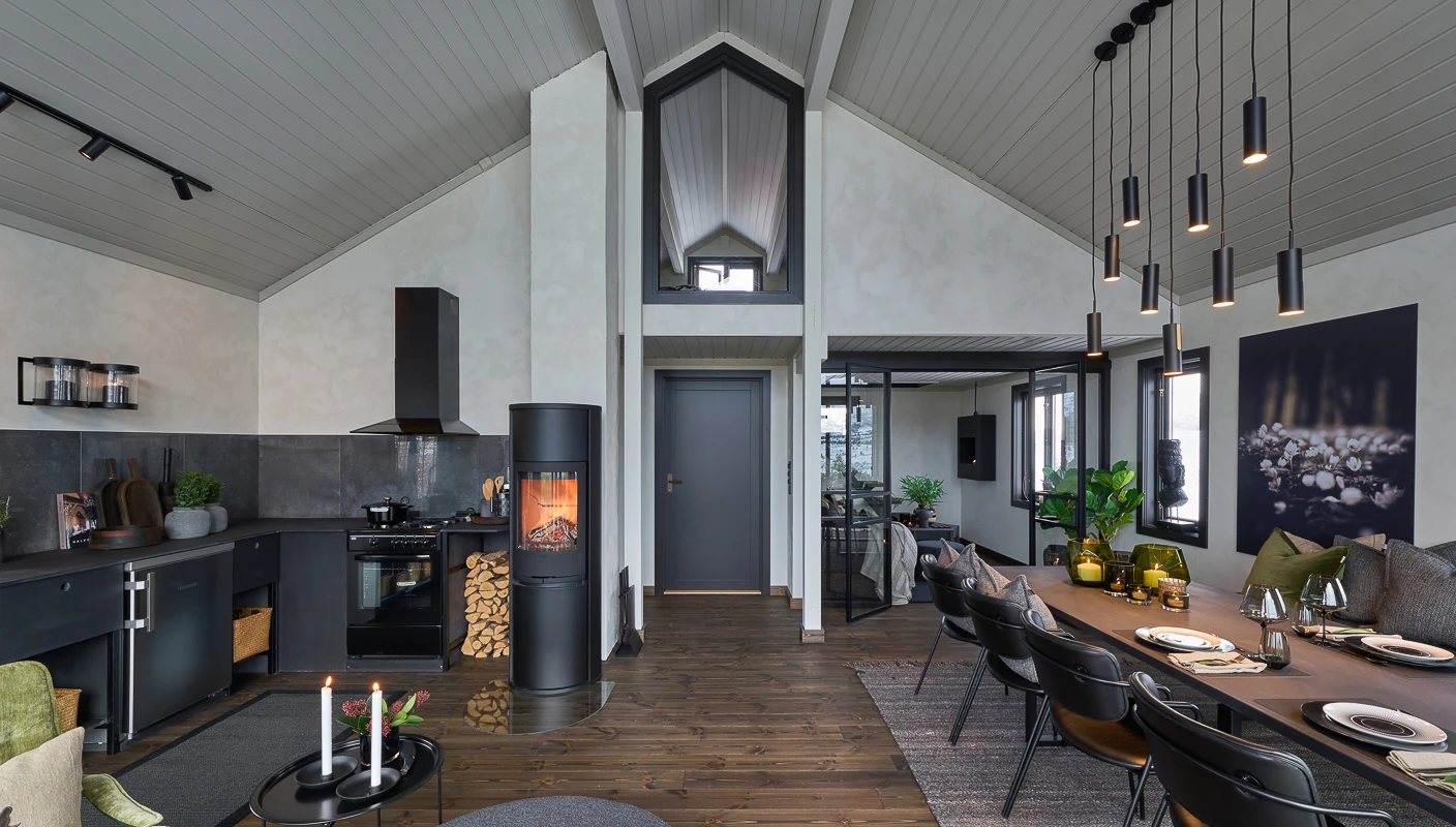 Åpen stue og kjøkkenløsning på hytte, malt panel i gråbeige i fargen Ascott i tak, og vegger malt med Jotun LADY Minerals kalkmaling i lys gråhvit Sommersne