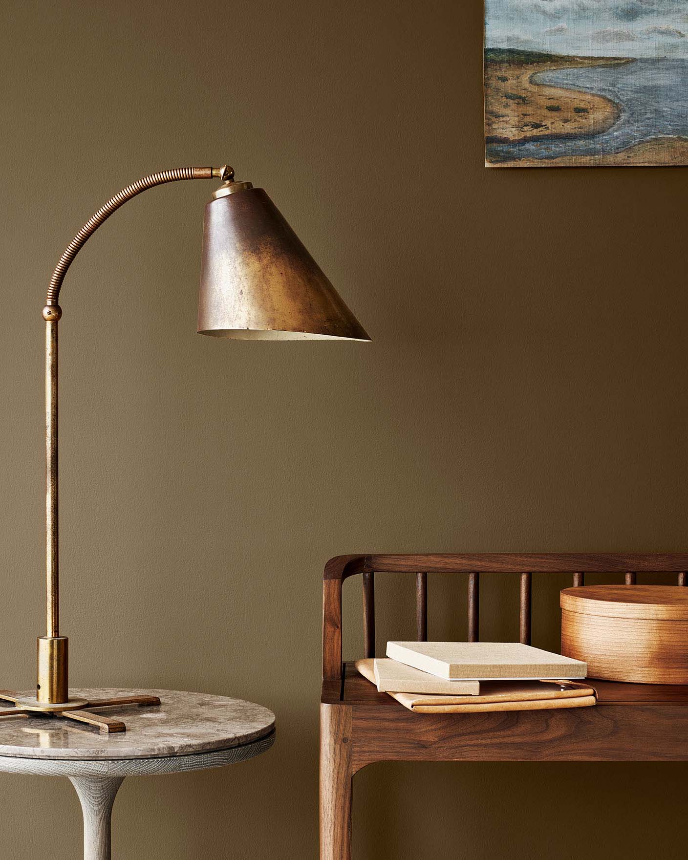 Messinglampe på et marmorbord ved siden av en trebenk, mot en gyldenbrun vegg malt med Jotun 10963 Golden Bronze.