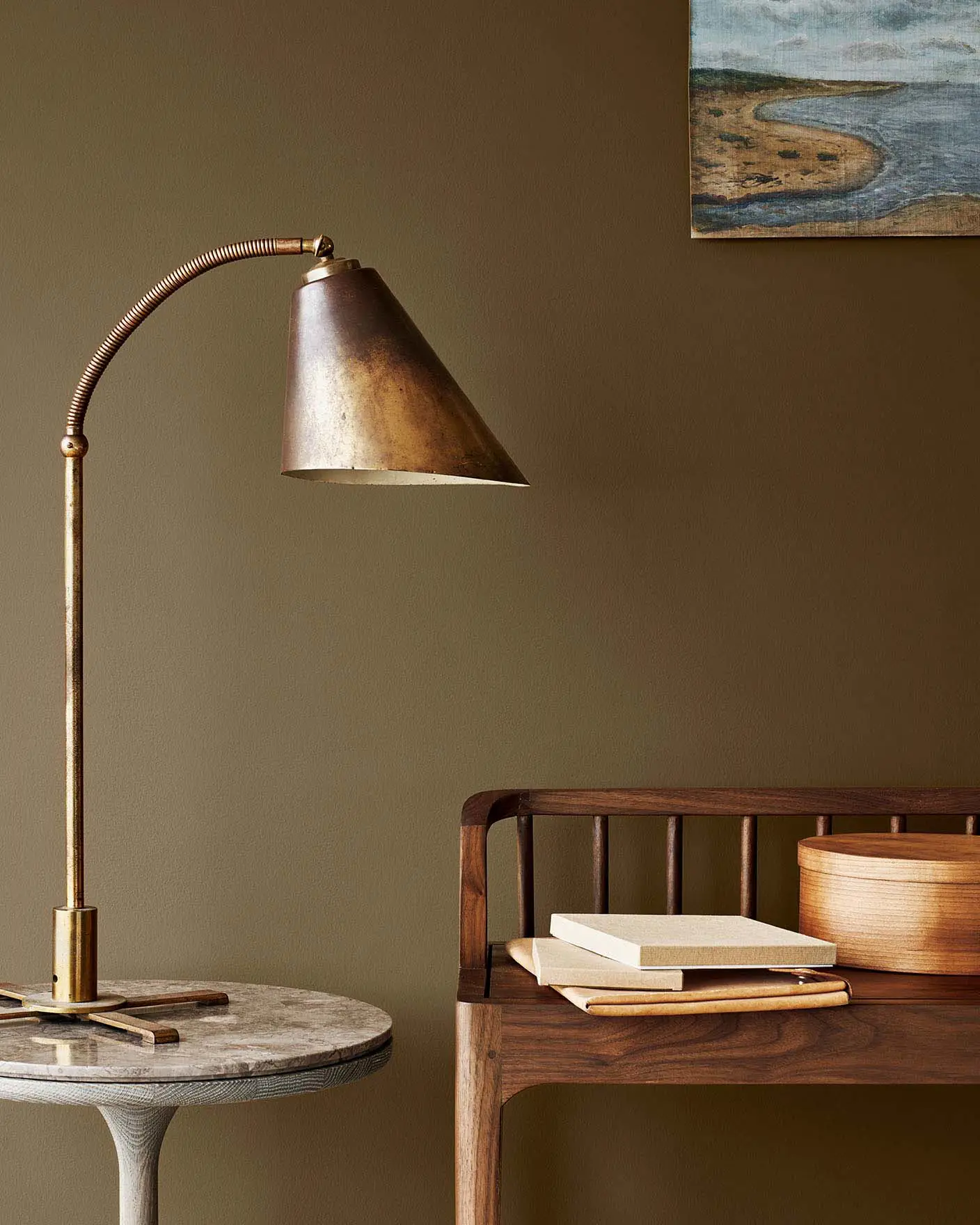 Messinglampe på et marmorbord ved siden av en trebenk, mot en gyldenbrun vegg malt med Jotun 10963 Golden Bronze.