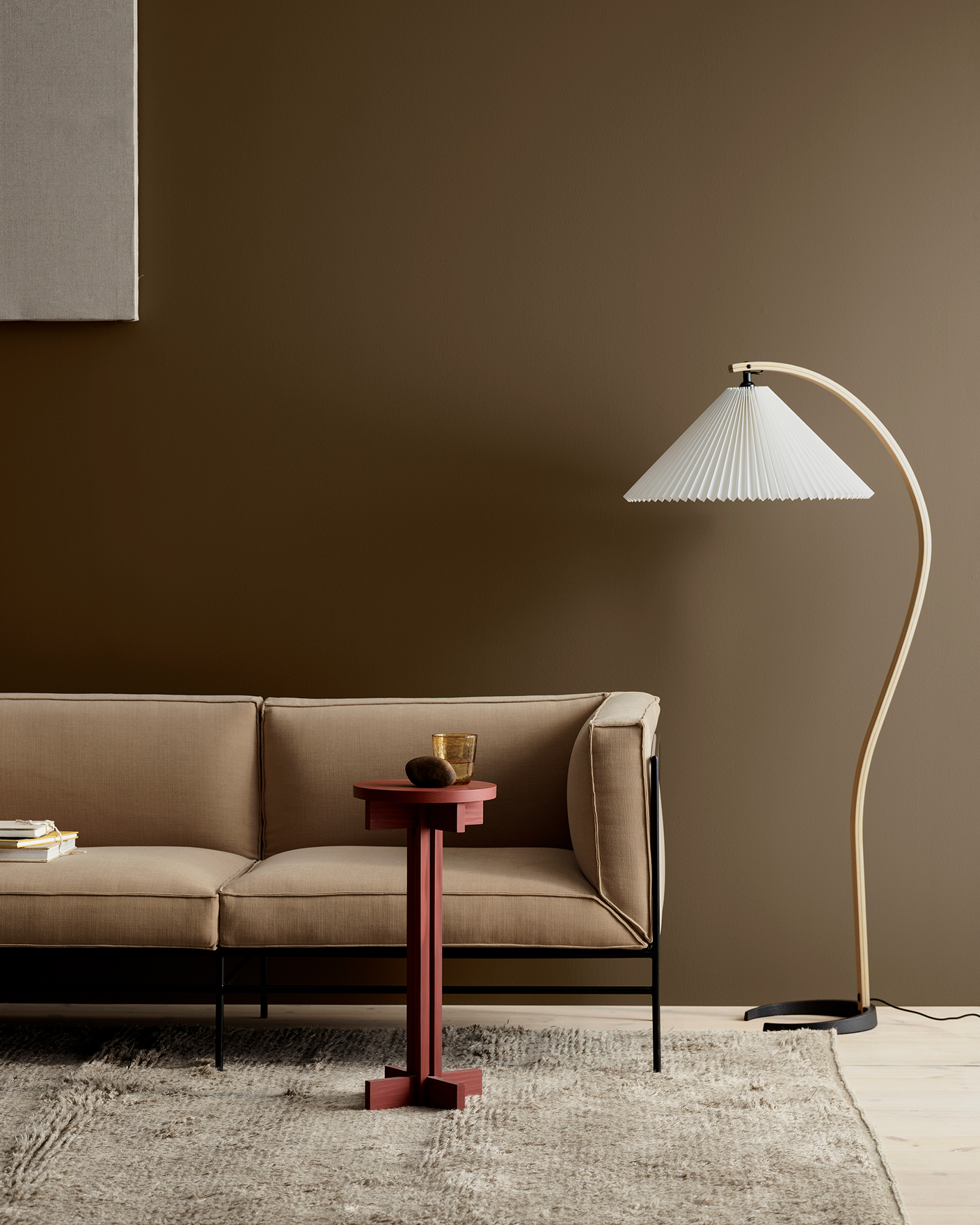 Soffa i beige färg med ett rött sidobord och en vit golvlampa i en stilfullt inredd interiör mot en brun vägg målad i 12291 Soft Brown.