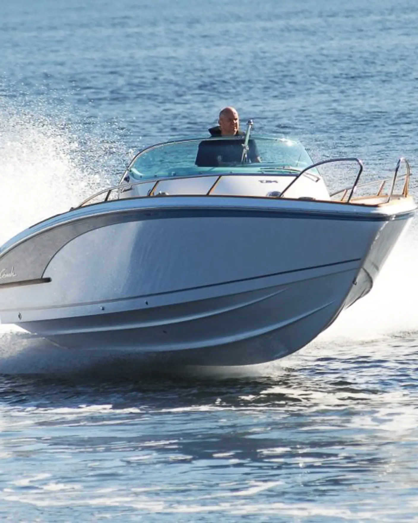 Mann styrer blank fritidsbåt i full fart på sjøen