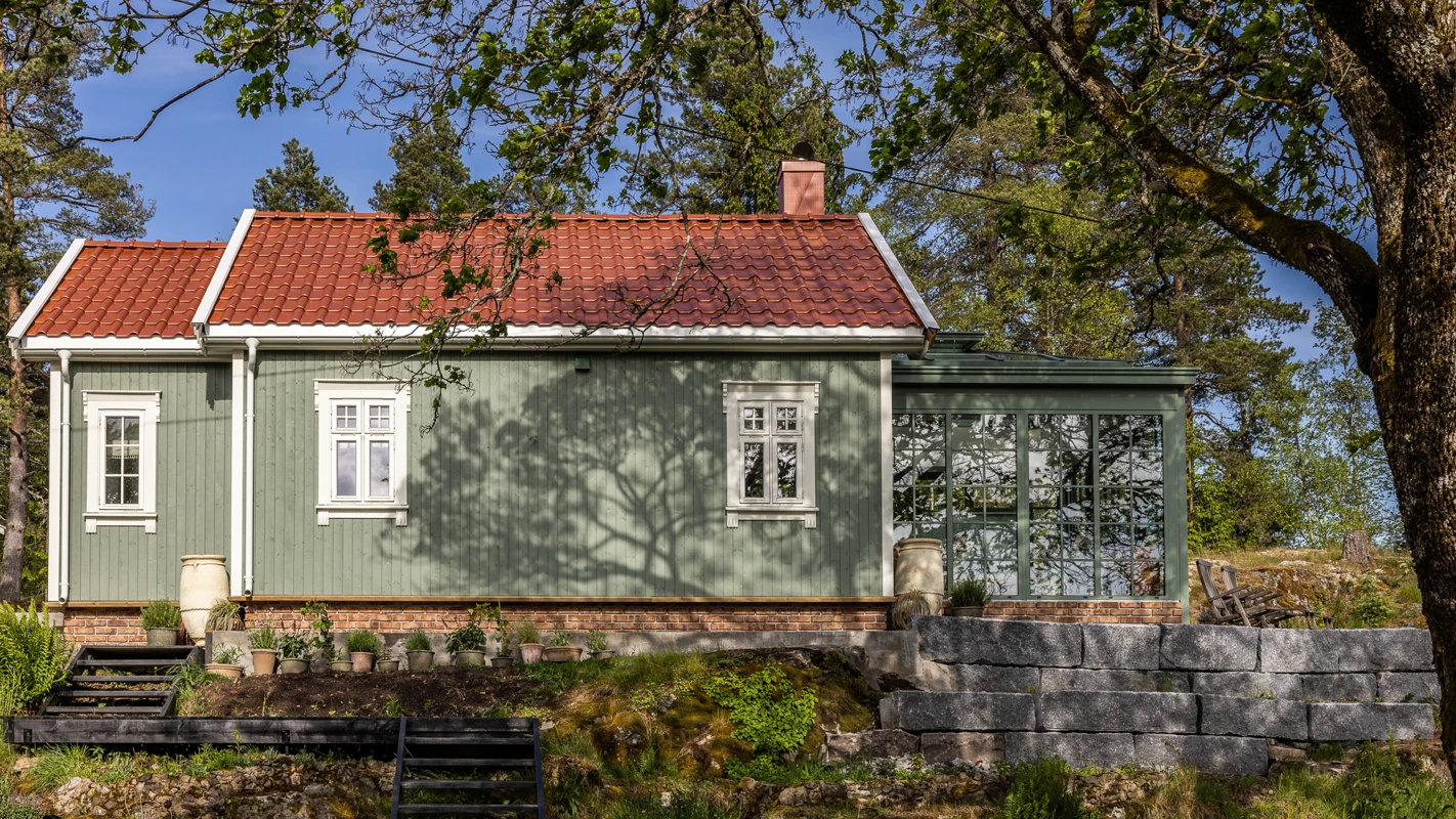 Grønt lite hus malt med Jotun Stockholmsgrønn med orangeri på enden og rødt tak