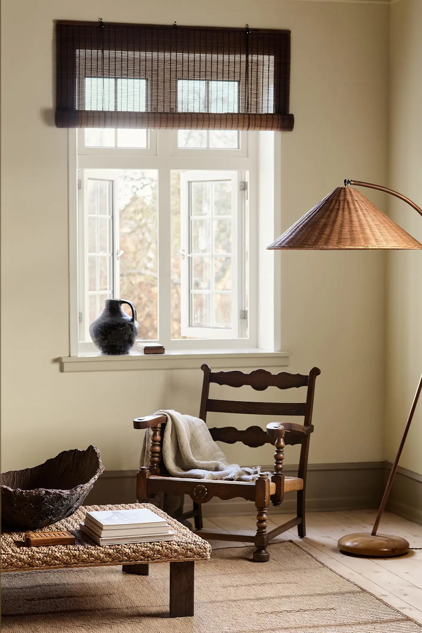 A wooden chair, woven lamp, and coffee table against a muted yellow wall painted in the colour 12080 Soft Radiance from Jotun.