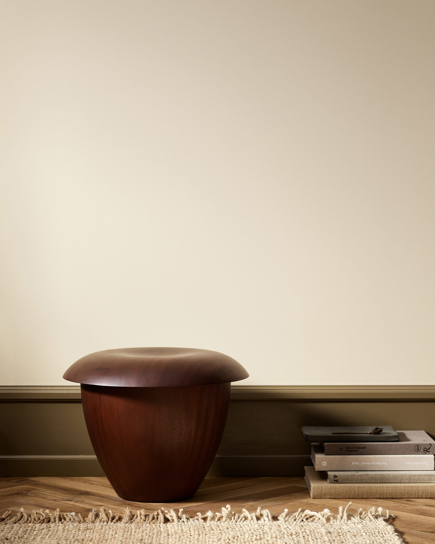 Wooden stool in a minimalist room with wall painted with Jotun 12313 Soft Dunes.