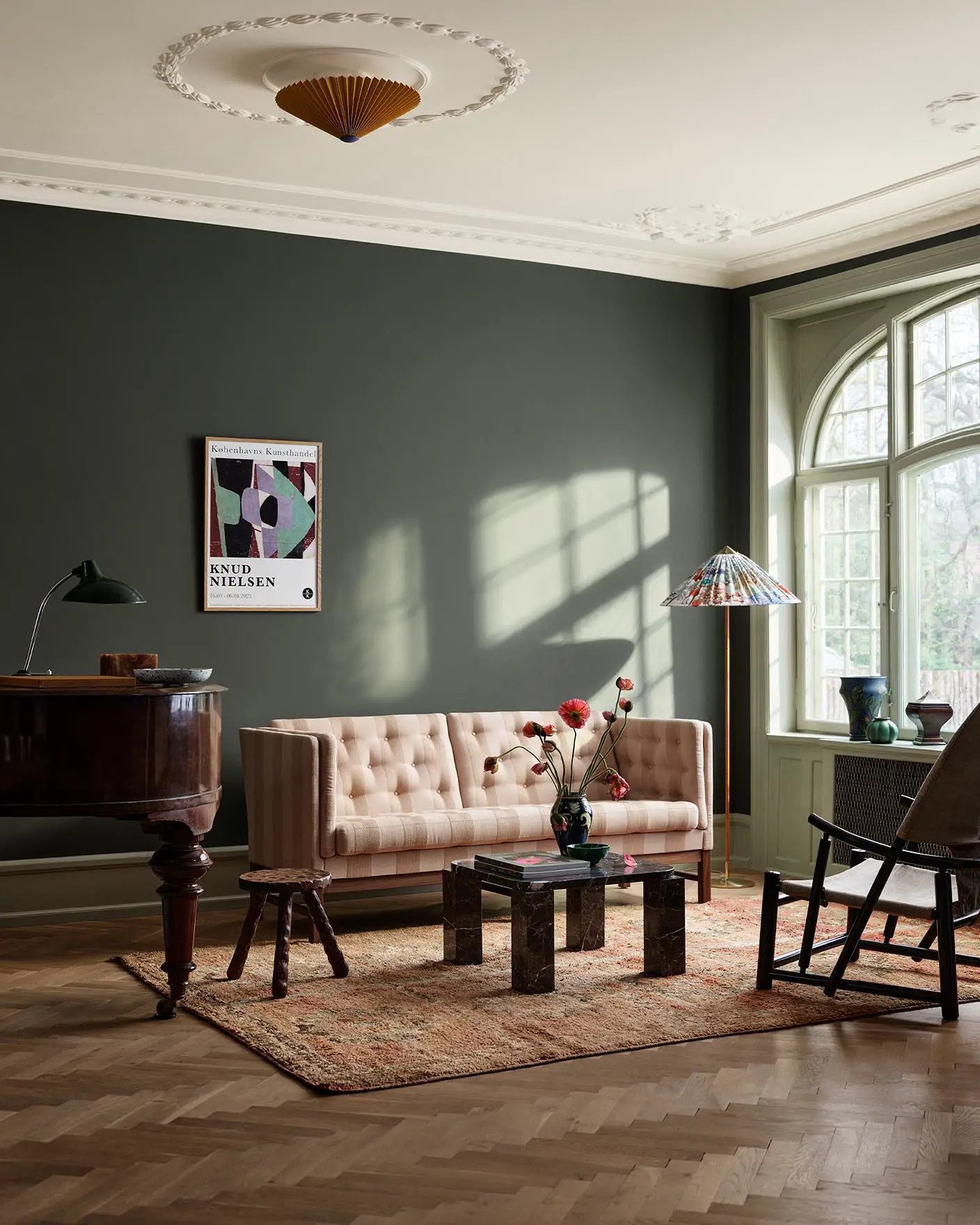 Living room with beige sofa, wooden table, and decor against a dark, muted green wall painted with the colour Jotun 7613 Northern Mystic.