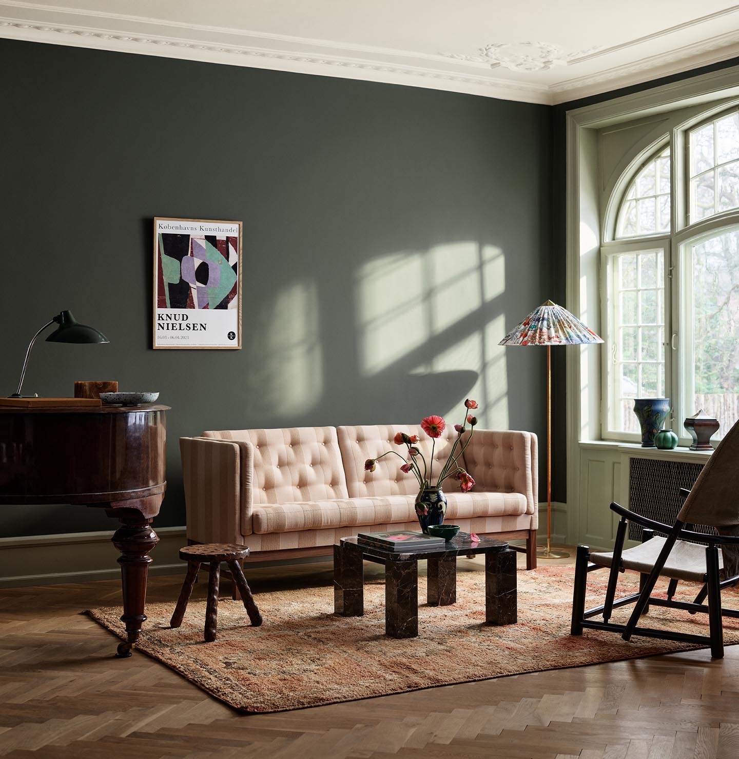 Living room with beige sofa, wooden table, and decor against a dark, muted green wall painted with the colour Jotun 7613 Northern Mystic.