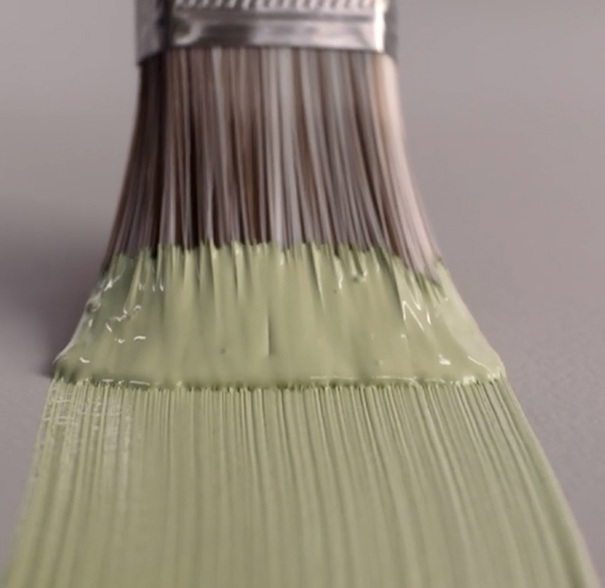 Malekost med lys grønn maling på børste, nærbilde mot grå bakgrunn