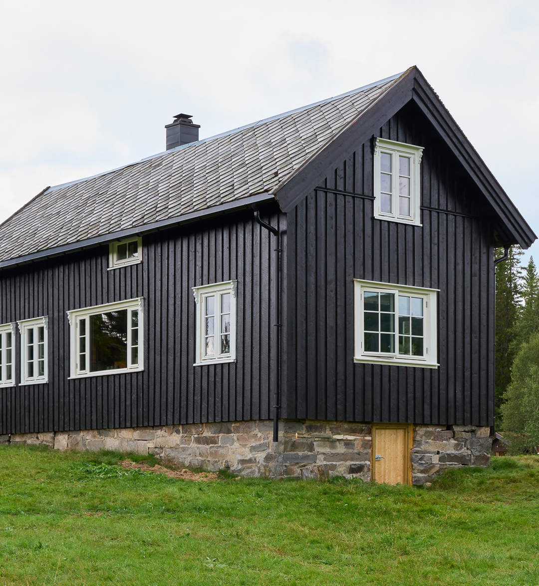 Hytte med skifertak malt i mørk brun, Seterbrun, Jotun DRYGOLIN, vinduer med sprosser og hvite karmer malt i Jotun Egghvit.