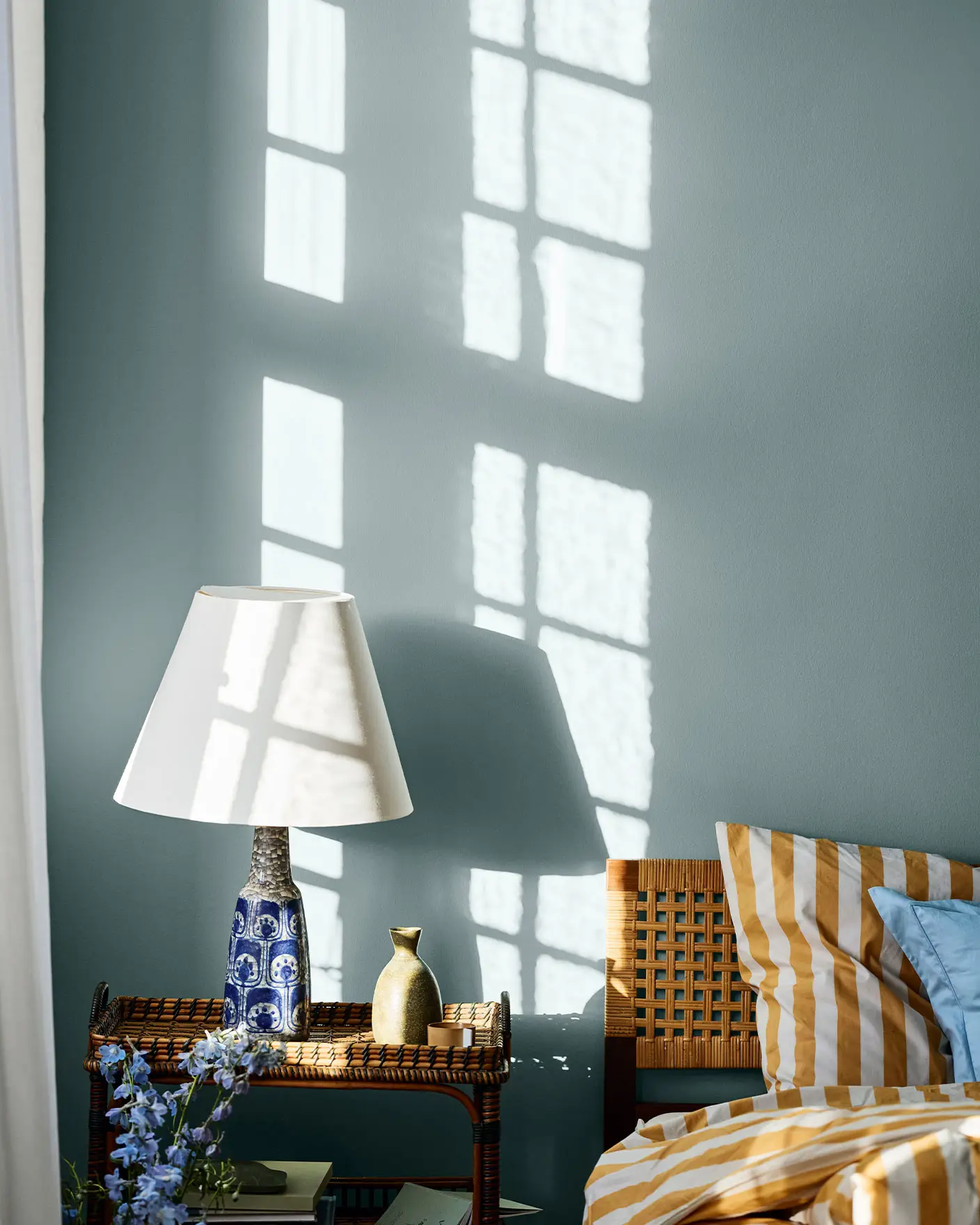 Soverom med seng og lampe, veggene er malt med Jotun 6236 Darjeeling. Sengetøyet er stripete i gult og hvitt.