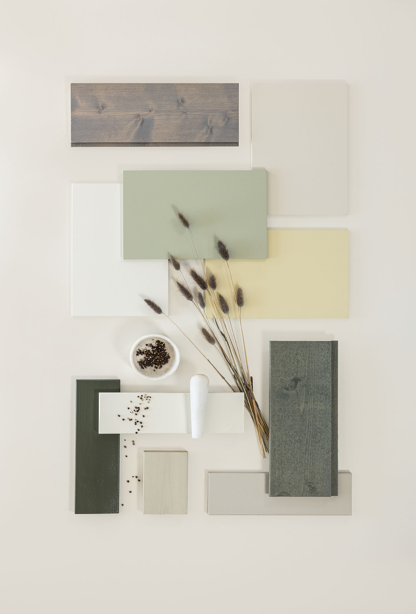 Fargeprøver i jordtoner, inkludert grønt, beige og tretekstur, arrangert med dekorative frø og tørkede stilker på en lys bakgrunn