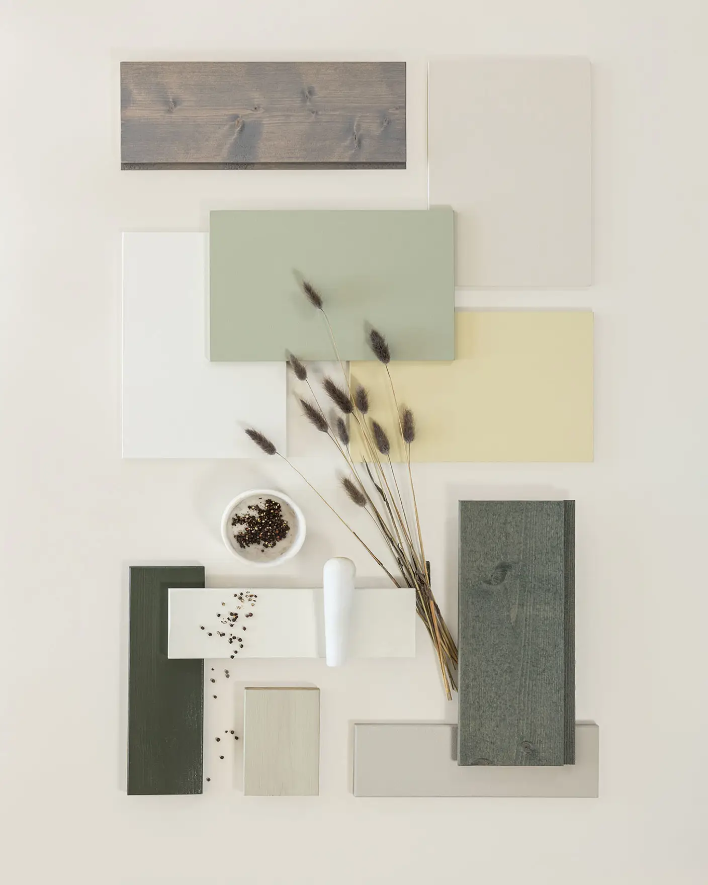 Fargeprøver i jordtoner, inkludert grønt, beige og tretekstur, arrangert med dekorative frø og tørkede stilker på en lys bakgrunn