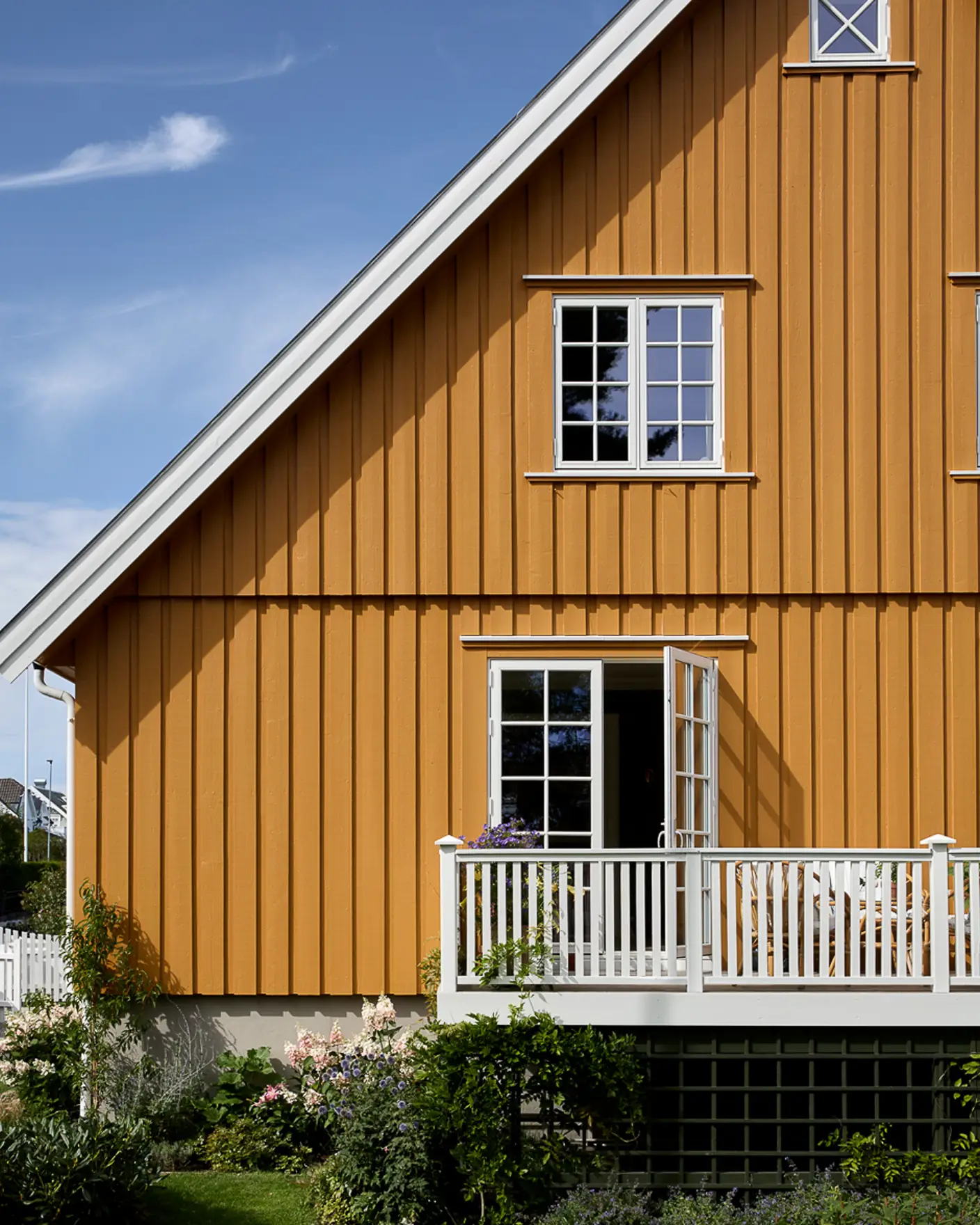 Klassisk villa med saltak, småsprossede vinduer og åpen terrassedør, fasade malt i dypt okergule JOTUN 0152 Staverngul og detaljer i hvit JOTUN 1001 Egghvit.
