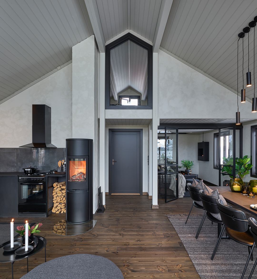 Stue med høyt under tak og sorte interiørdetaljer i industriell stil, vegger malt med kalkmaling Jotun LADY Minerals i gråhvite Sommersne.
