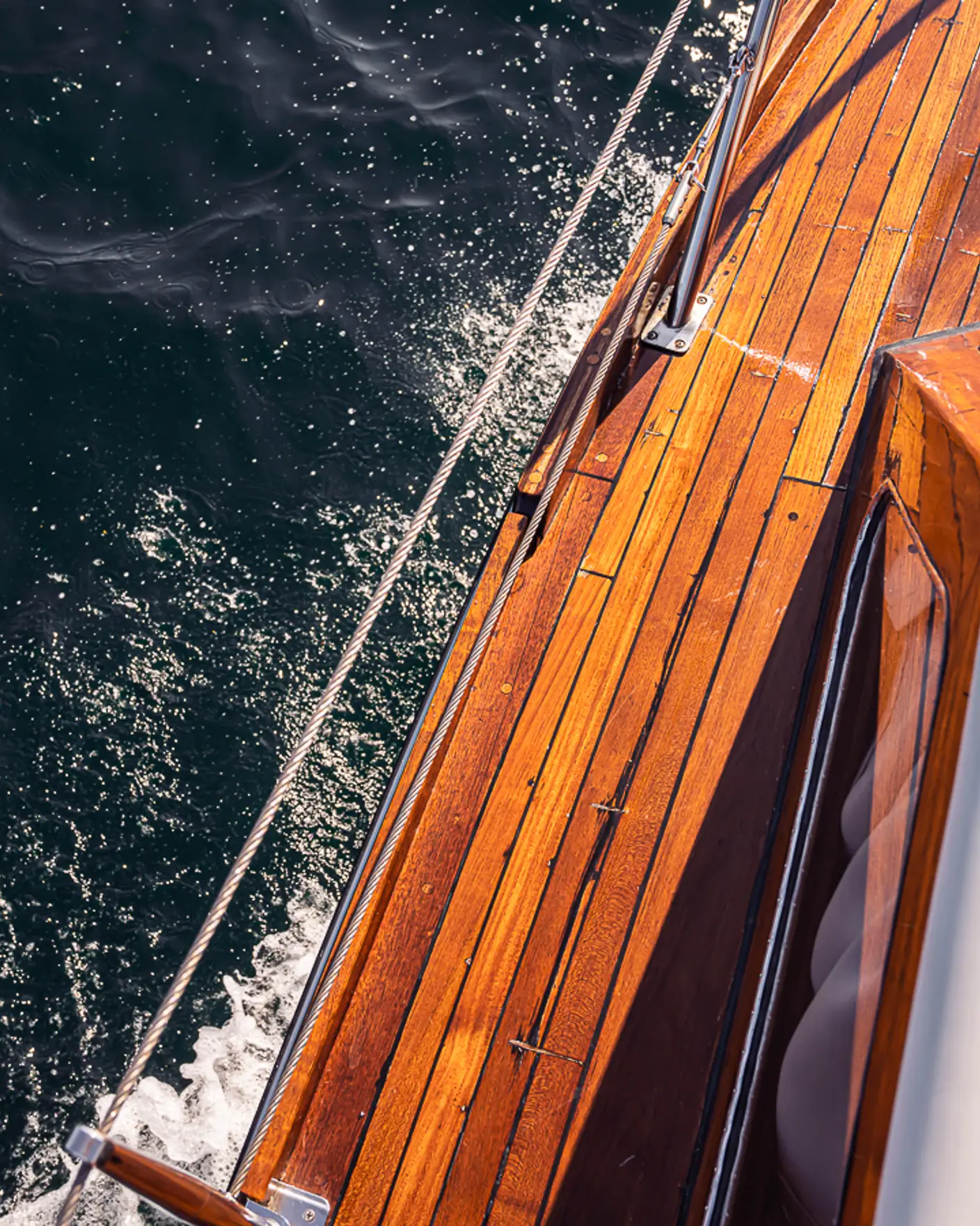 Utsnitt av siden på en blank trebåt sett ovenfra, som skjærer gjennom vannet.
