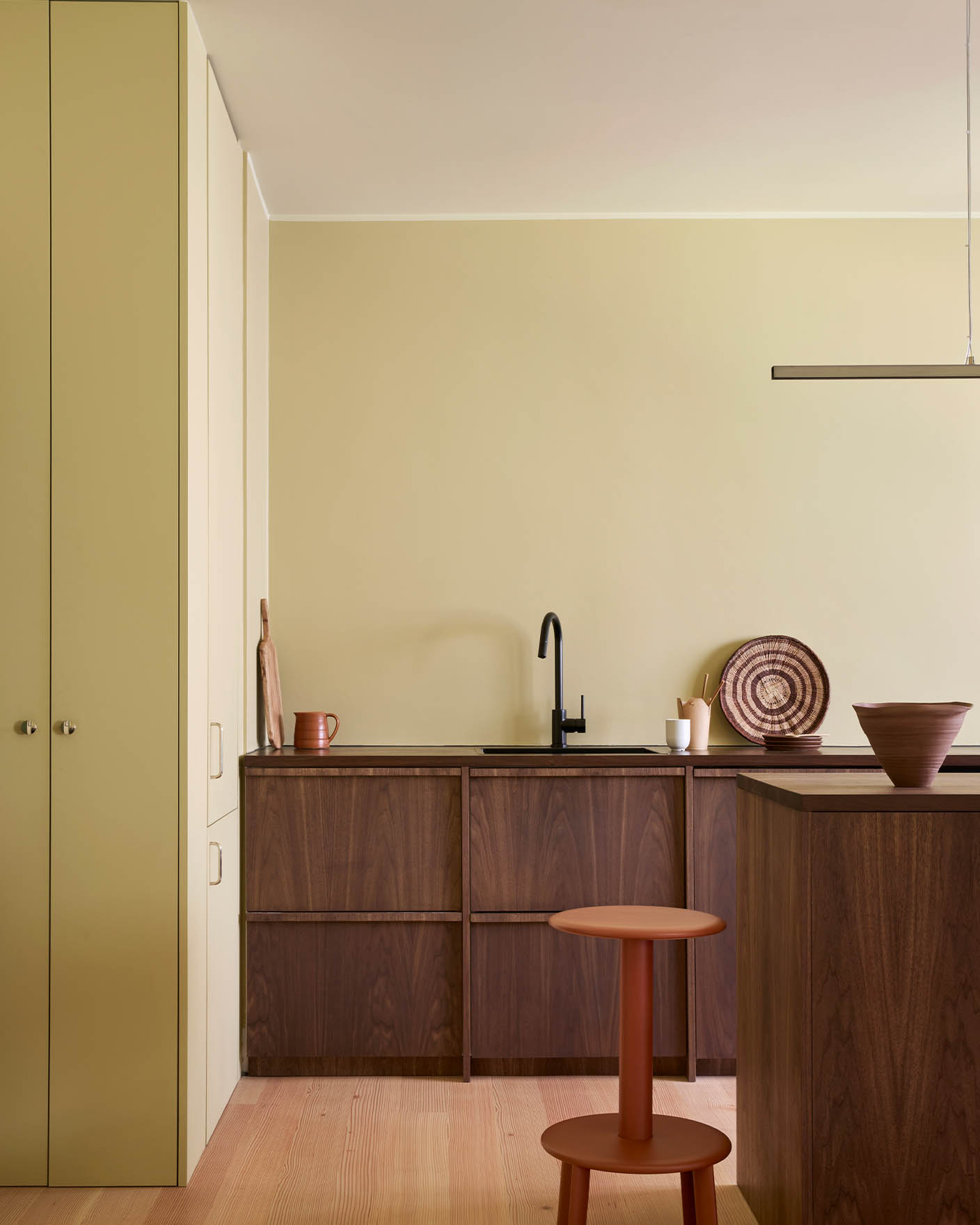 Kitchen walls painted in Jotun Earty Yellow with cabinetry in dark solid Walnut