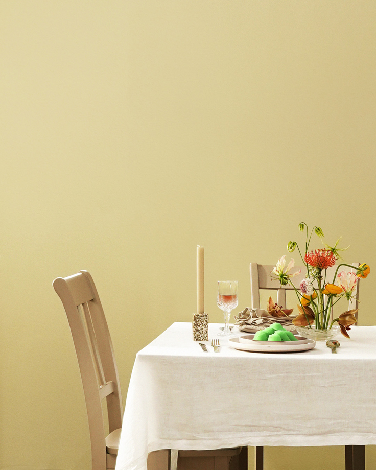 Meja makan dengan dinding Jotun Ginger Tea 1965 Majestic Pure Color, menampilkan dekorasi bunga dan hidangan untuk inspirasi interior