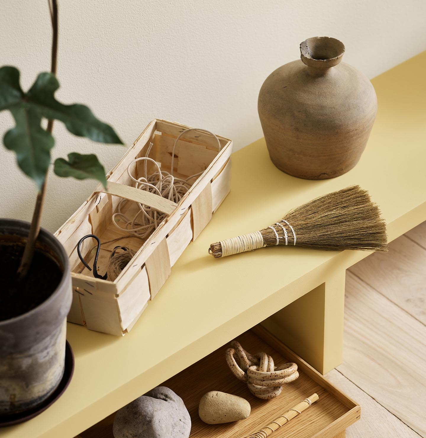 A yellow bench in the Jotun colour 1965 Ginger Tea against a golden, white wall painted in 1625 Soul.