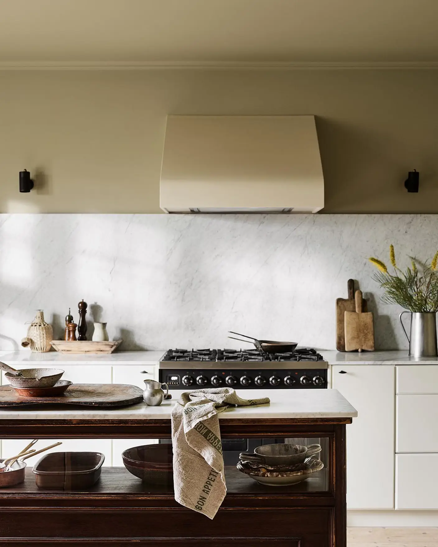 Kitchen with a marble backsplash, white cabinets, and a wooden island. Wall painted with the Jotun colour 8284 Olive.