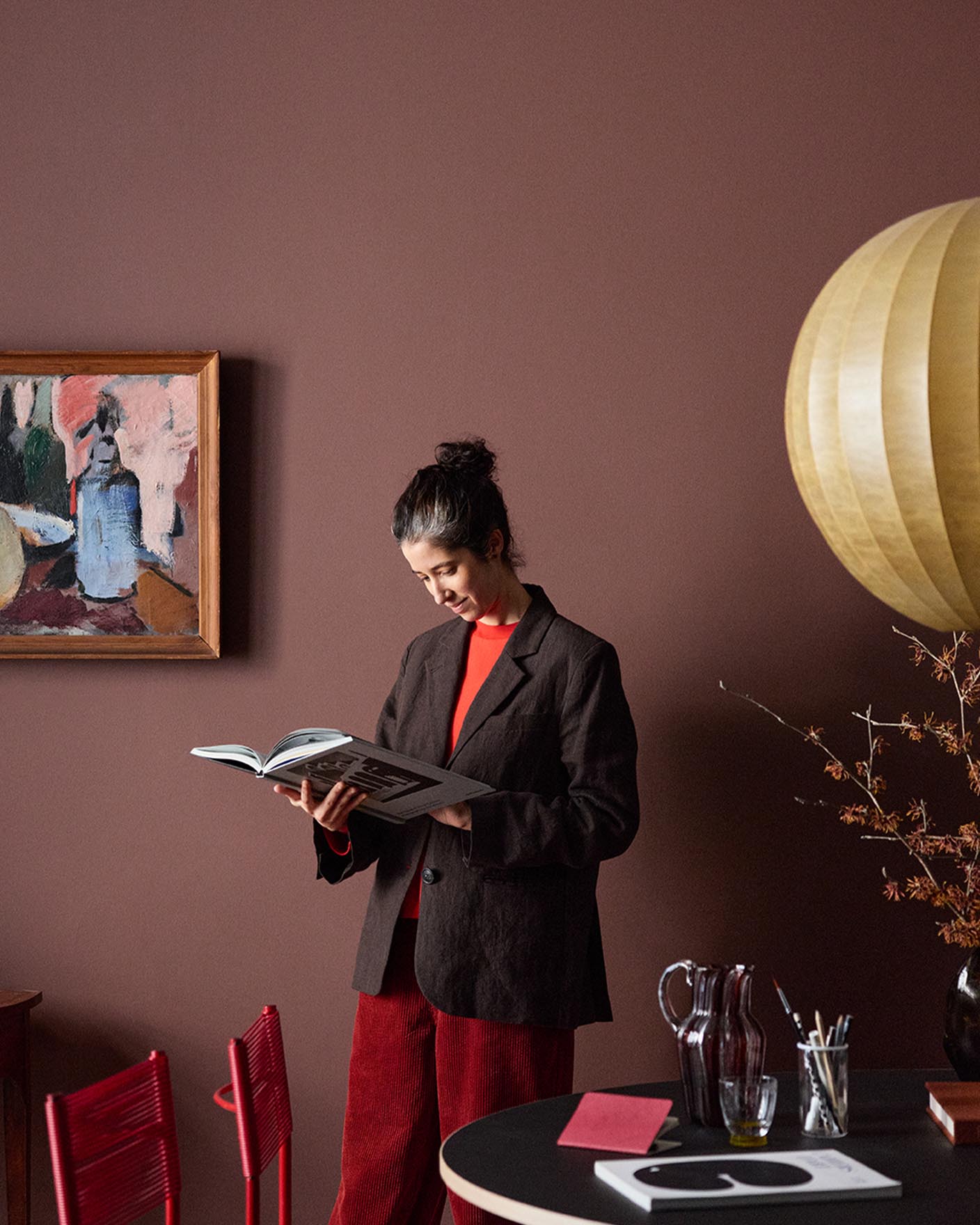 Woman standing reading in front of a deep red wall painted with Jotuns colour 2951 Sophisticated Red.