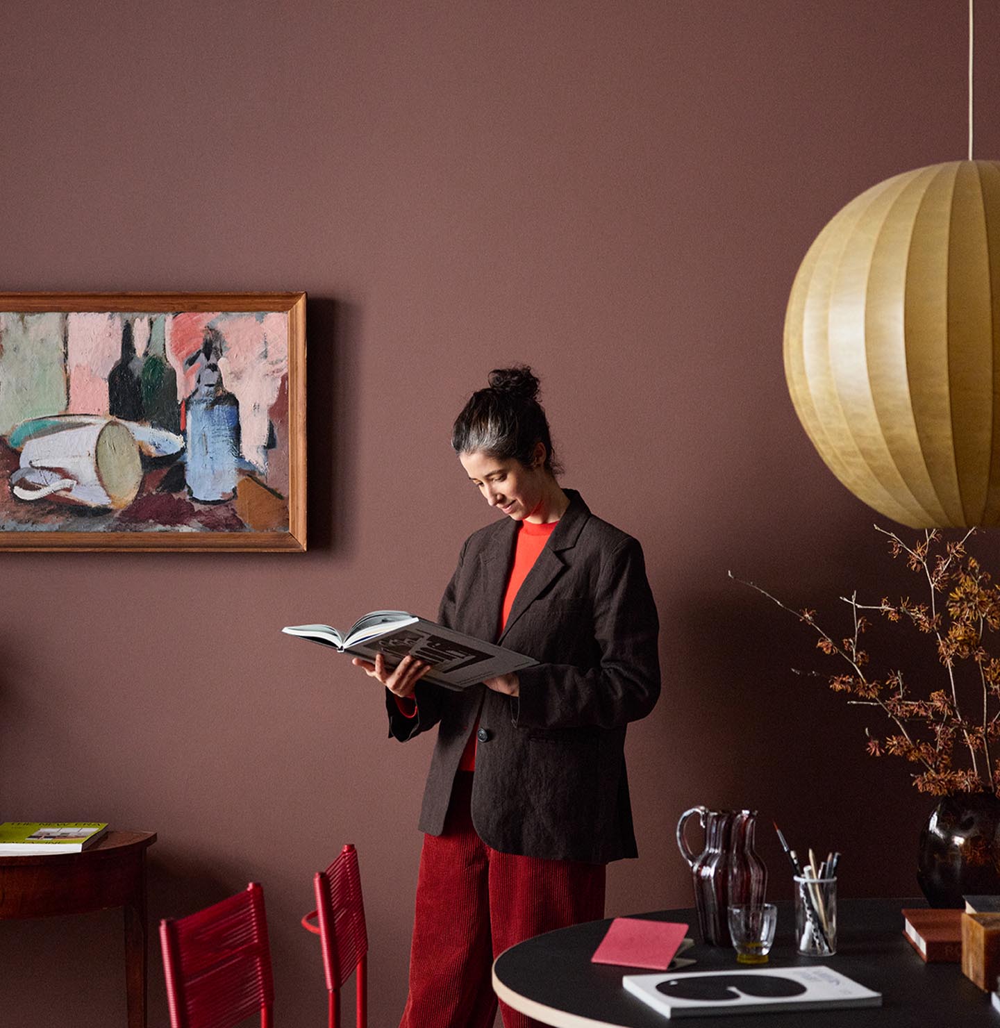Woman standing reading in front of a deep red wall painted with Jotuns colour 2951 Sophisticated Red.