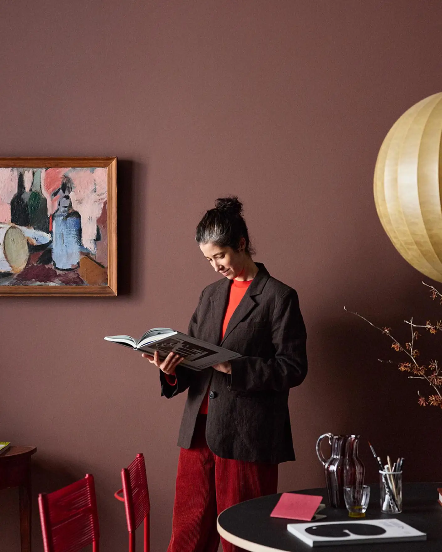 Woman standing reading in front of a deep red wall painted with Jotuns colour 2951 Sophisticated Red.