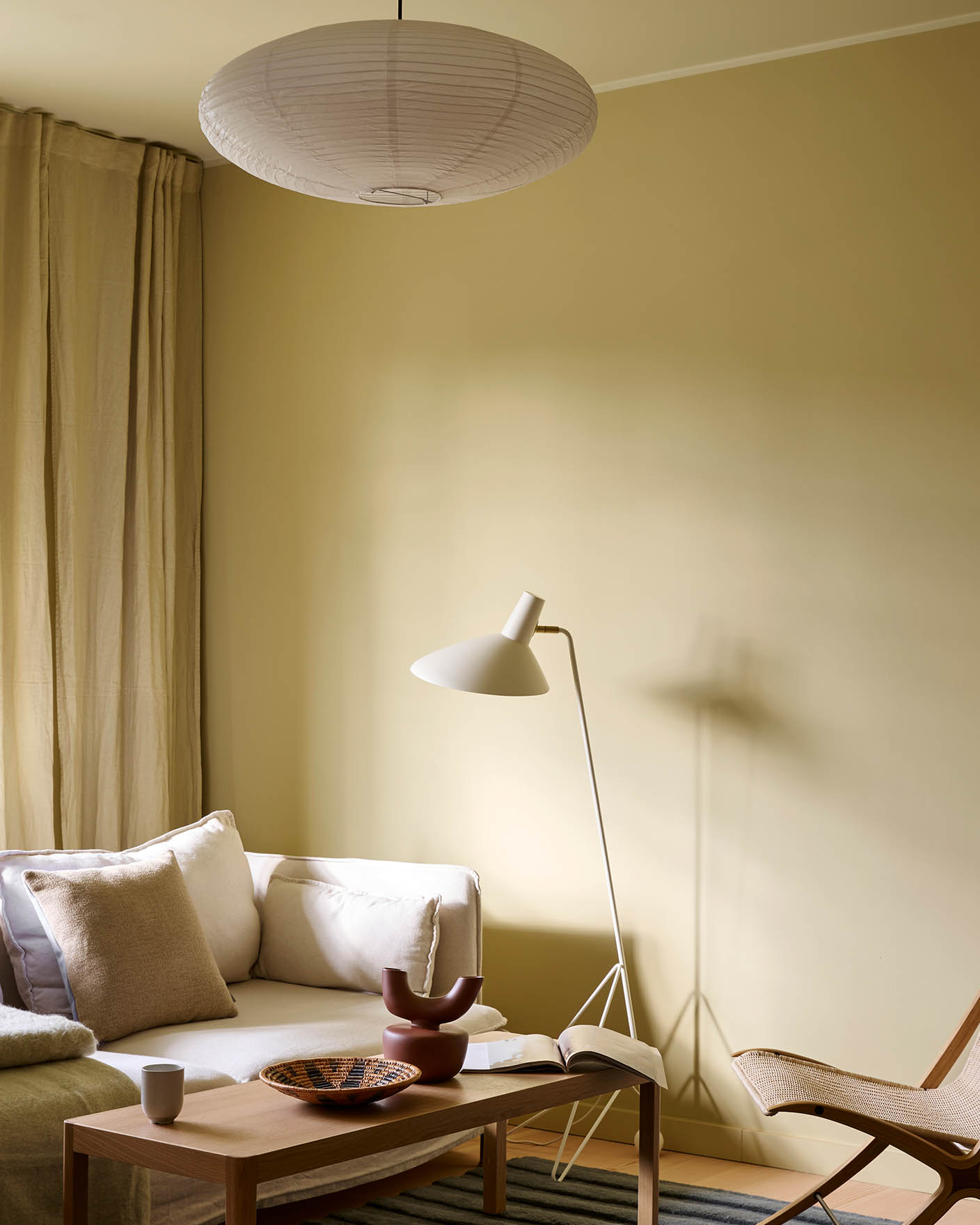 Bright living room with walls in Jotun Humble Yellow, white sofa, beige curtains, and ceiling painted in Malmø.