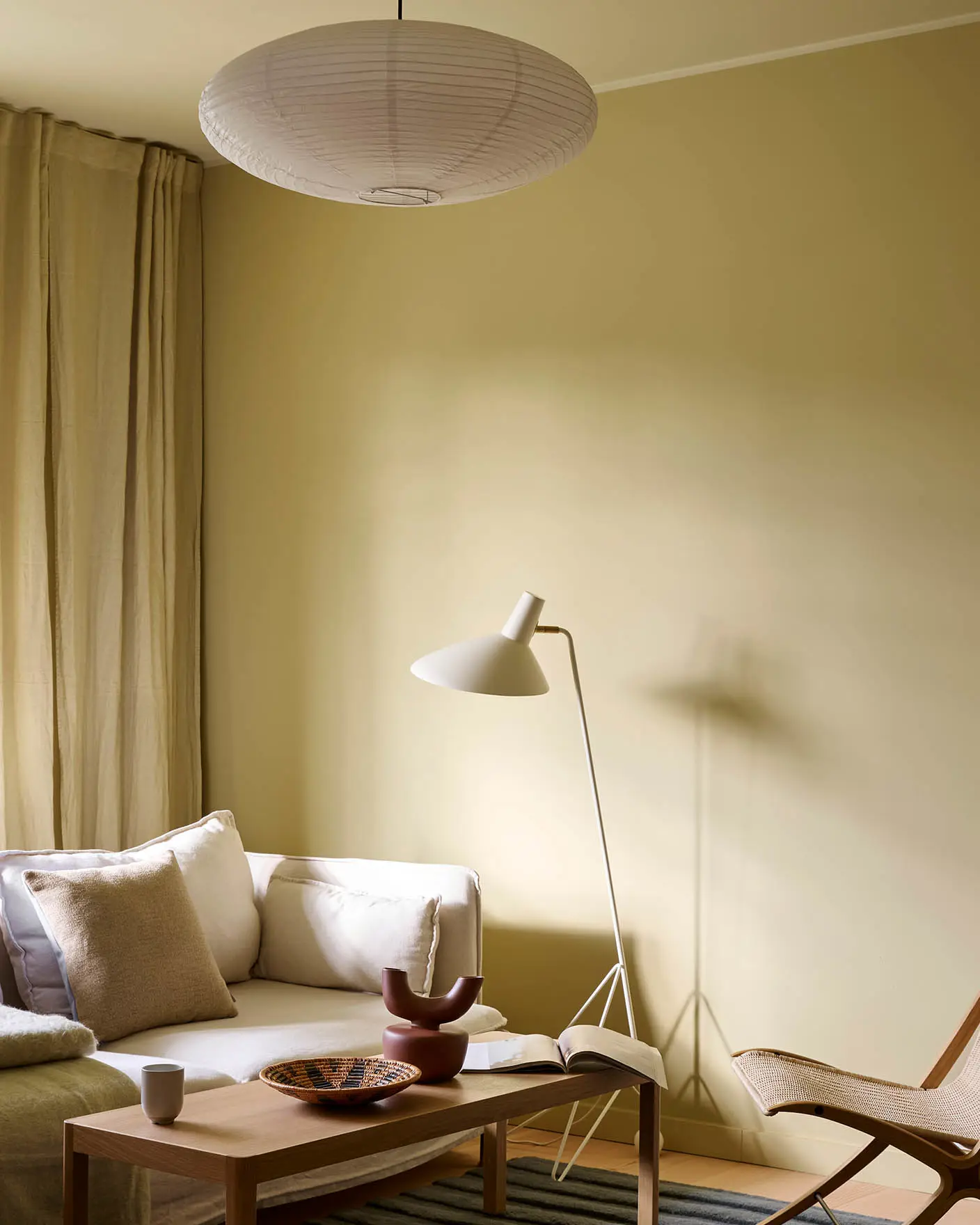 Bright living room with walls in Jotun Humble Yellow, white sofa, beige curtains, and ceiling painted in Malmø.