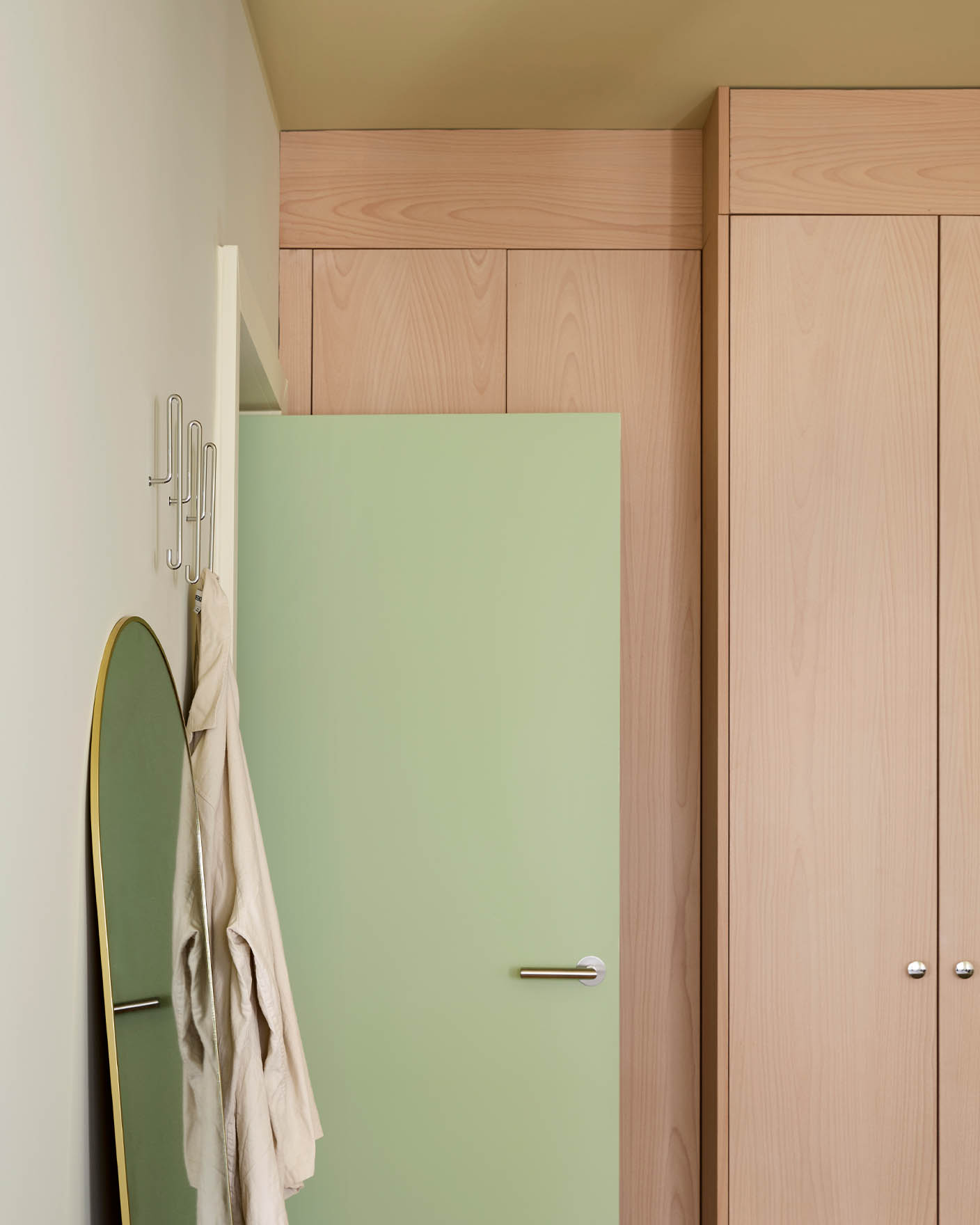 Avocado Green door in front of tall light wood cabinets. Walls painted in Jotun Malmoe and ceiling with Earthy Yellow. 