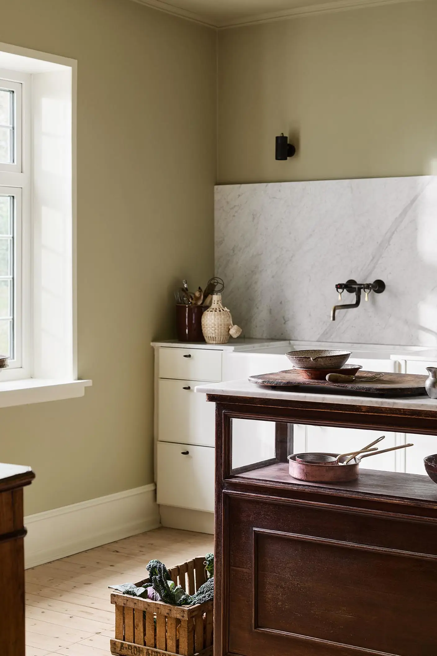 Kitchen with a marble backsplash, white cabins and a wooden island. Walls and ceiling painted with the Jotun colour 8284 Olive.