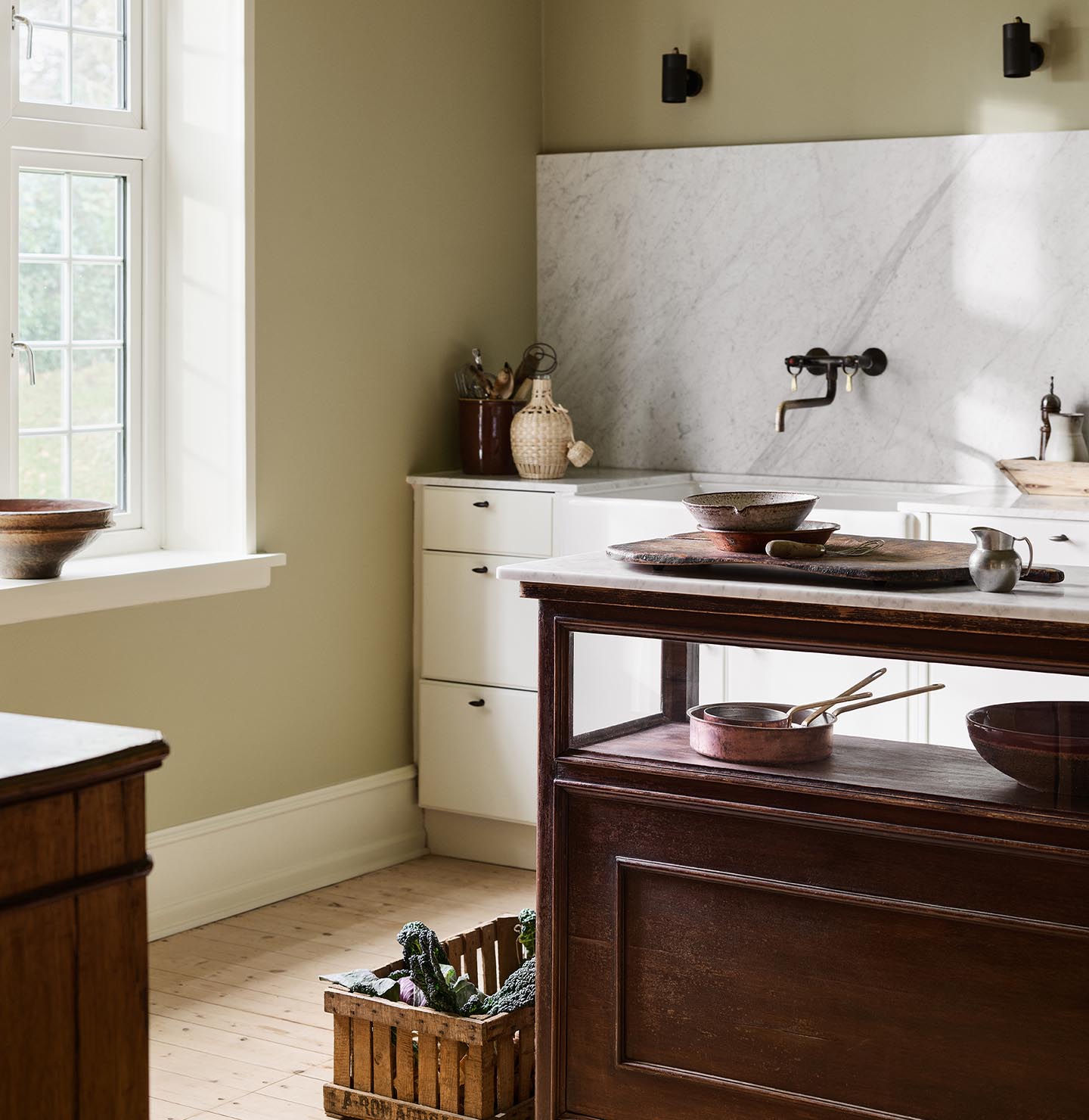 Kitchen with a marble backsplash, white cabins and a wooden island. Walls and ceiling painted with the Jotun colour 8284 Olive.