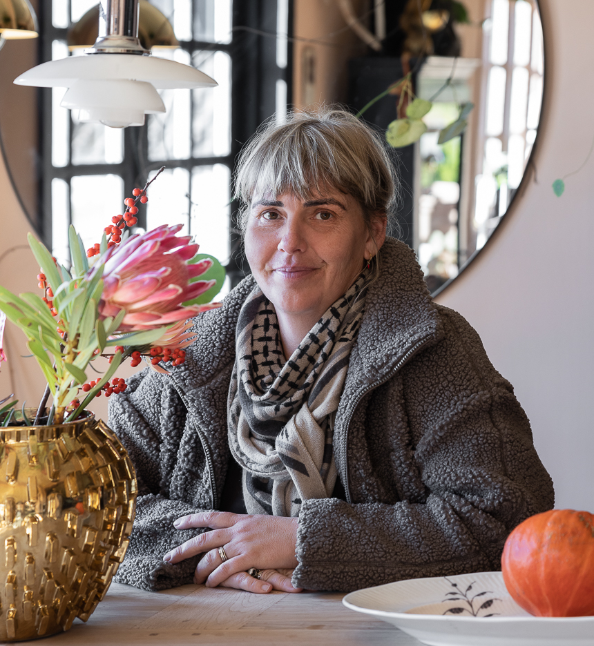 Portrett av Jane Ruby Krucov Jensen ved spisebordet i sin rosa stue malt i Jotun Pink Ambience