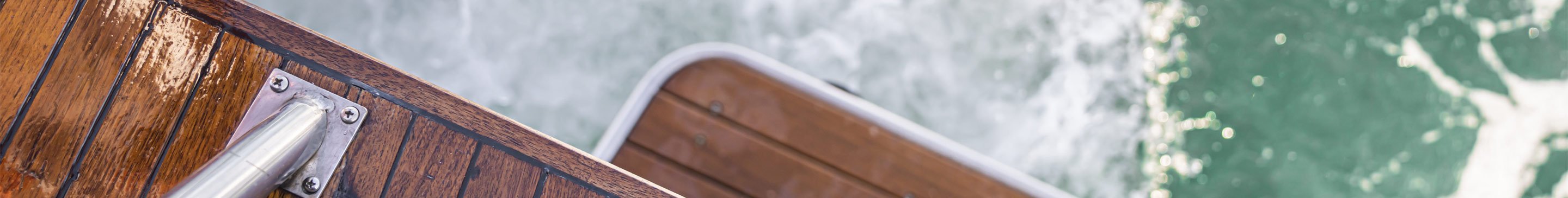 Tredekket badeplattform på en båt ved vannet, med bølger i bakgrunnen