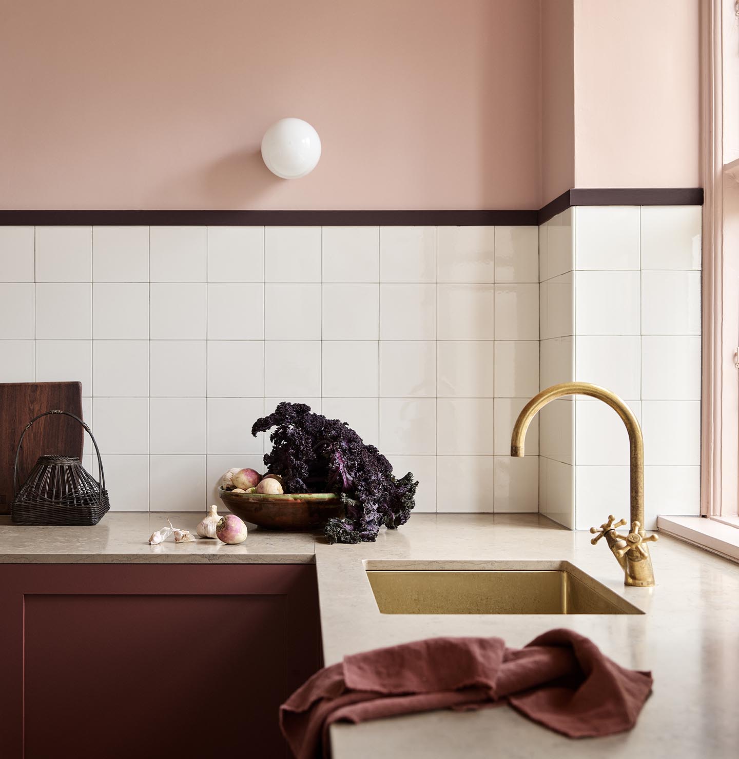 Kitchen counter with vegetables and decor against soft pink walls painted in the colour 20362 Pink Ambience from Jotun and white tile backsplash.