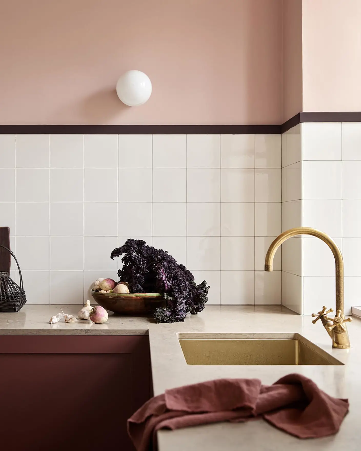 Kitchen counter with vegetables and decor against soft pink walls painted in the colour 20362 Pink Ambience from Jotun and white tile backsplash.