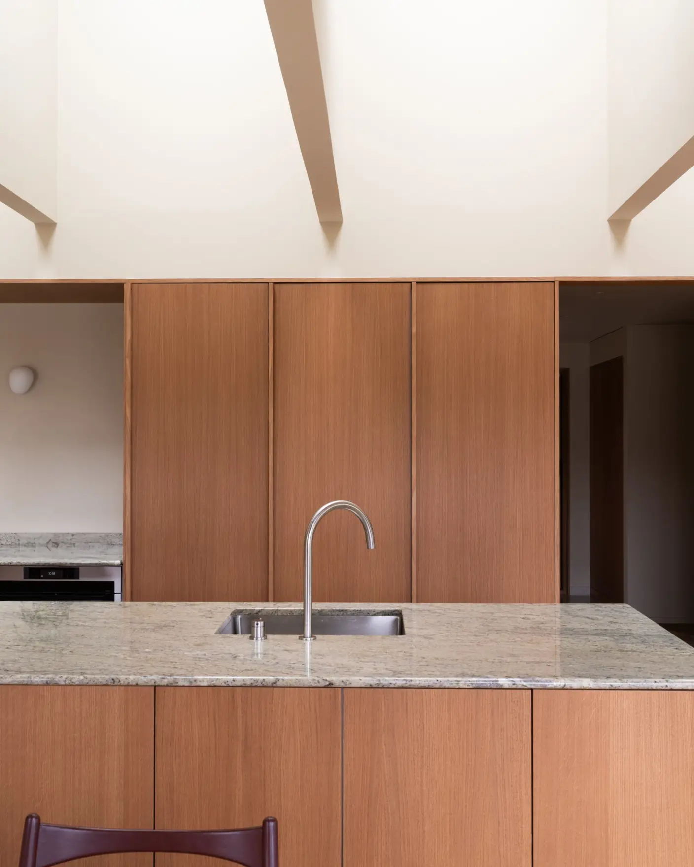 Moderne kjøkken interiør med treverk og gulbeige vegger og tak malt i Jotun 11173 Humble Yellow, grå benkeplate, og stilren kjøkkenvask