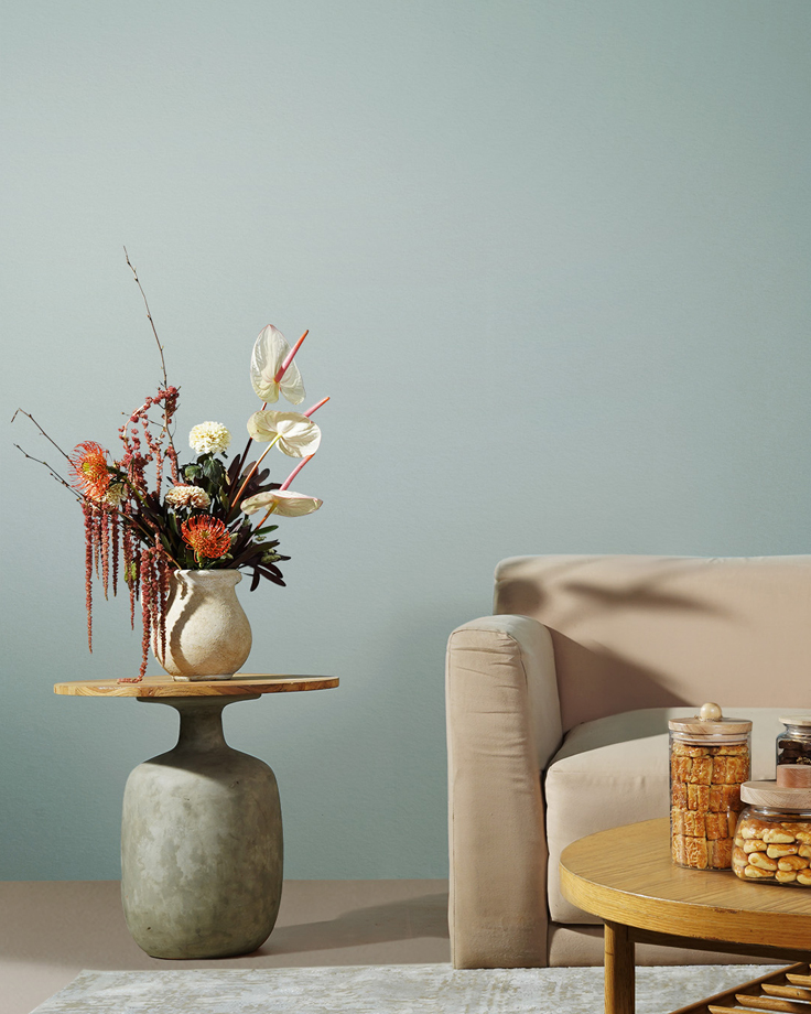 Ruang tamu dengan dinding Jotun Iconic 6378 Majestic Pure Color, menampilkan vas bunga di meja dan sofa krem untuk inspirasi interior