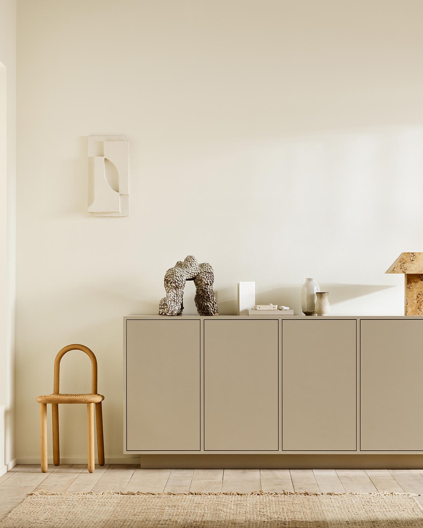 Minimalist interior with wooden chair, a cabinet painted with 12300 Hazelnut Beige against a beige wall painted in the colour Jotun 1625 Soul.