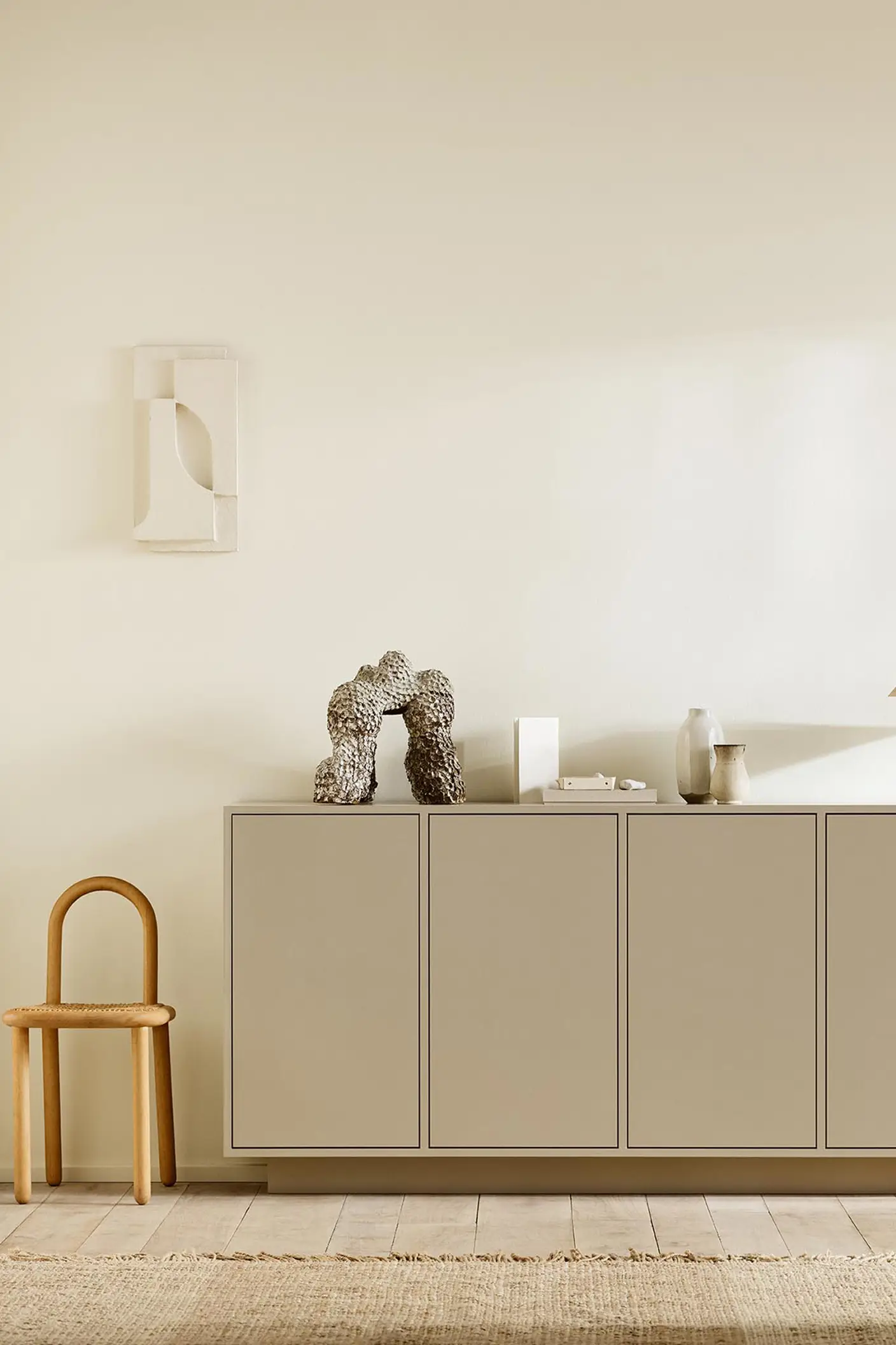 Minimalist interior with wooden chair, a cabinet painted with 12300 Hazelnut Beige against a beige wall painted in the colour Jotun 1625 Soul.