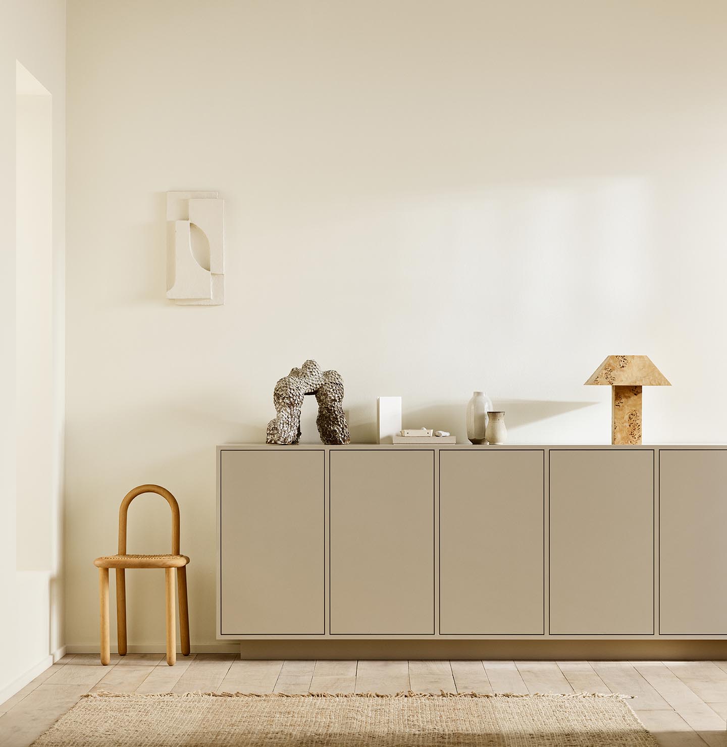 Minimalist interior with wooden chair, a cabinet painted with 12300 Hazelnut Beige against a beige wall painted in the colour Jotun 1625 Soul.